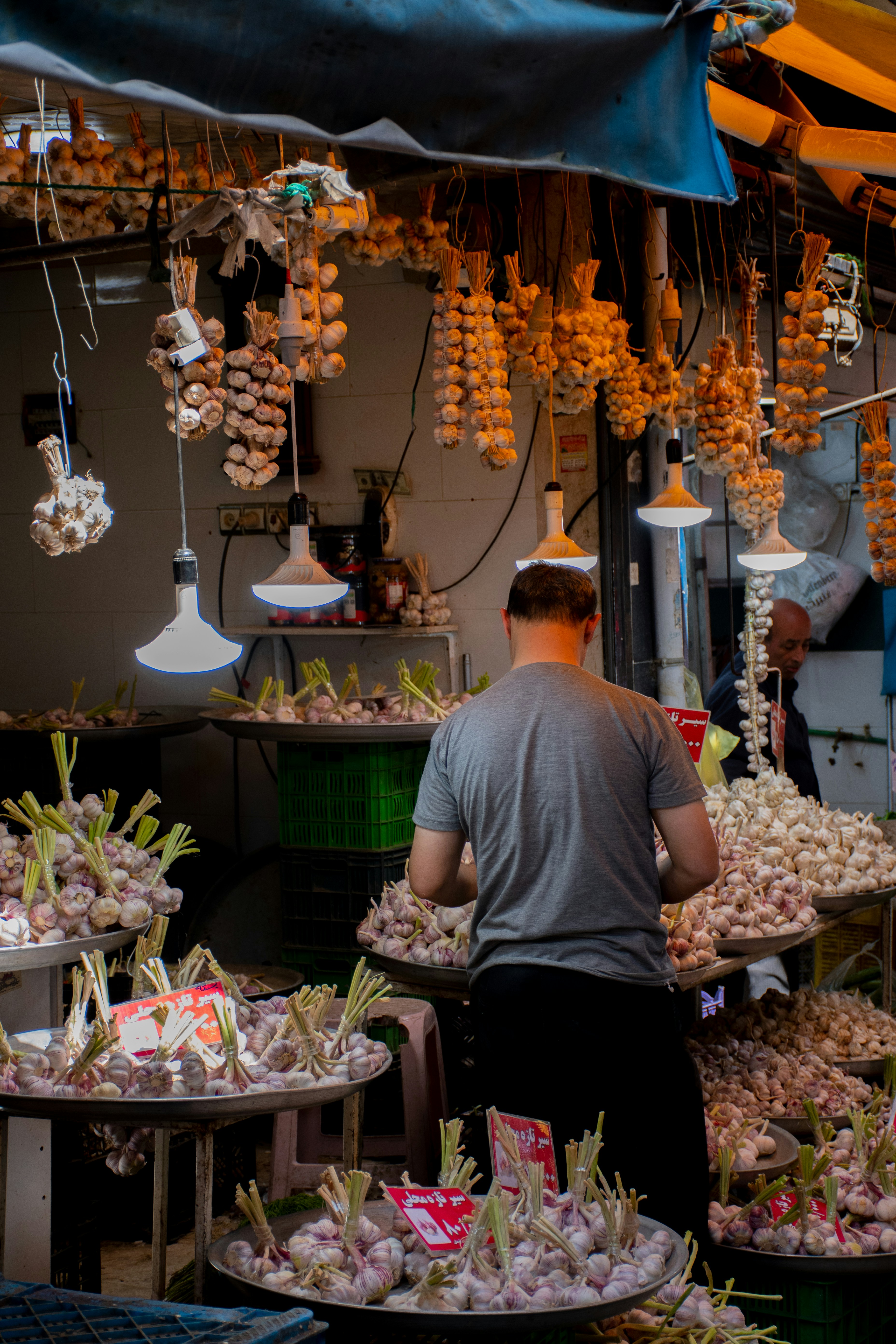 A vendor works at a garlic market stall.