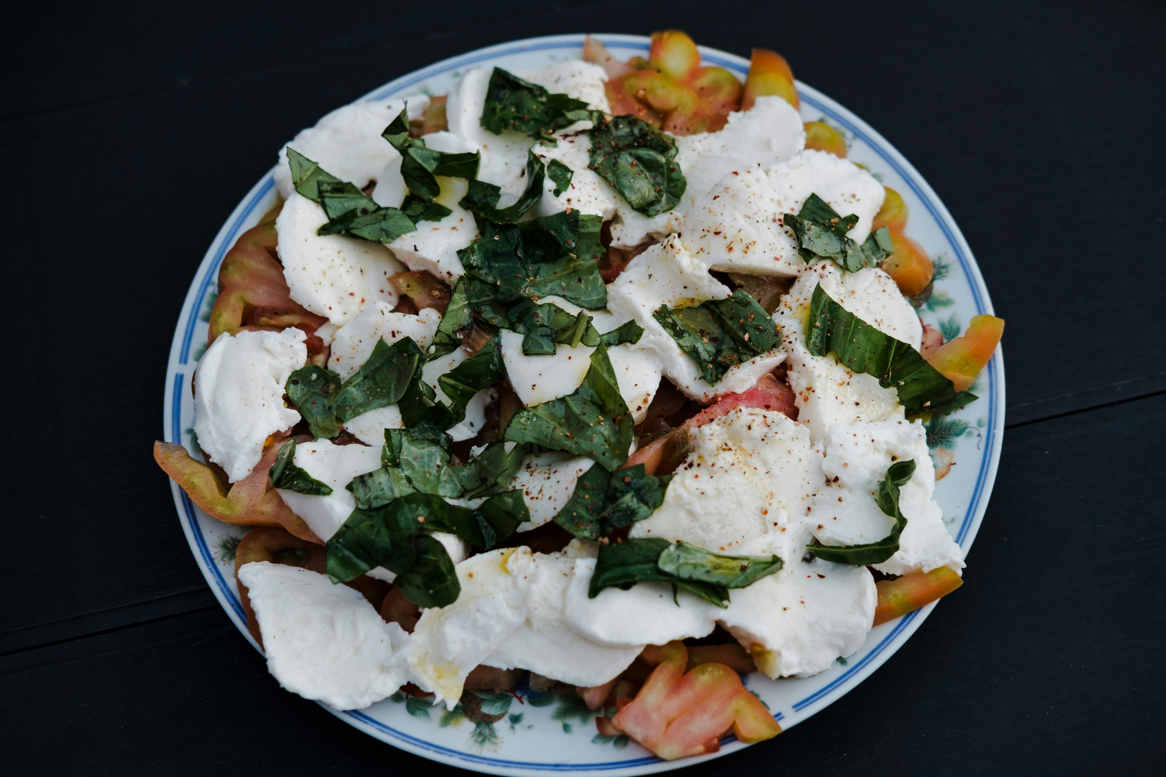 Heirloom tomatoes, mozzarella, and basil on a plate.