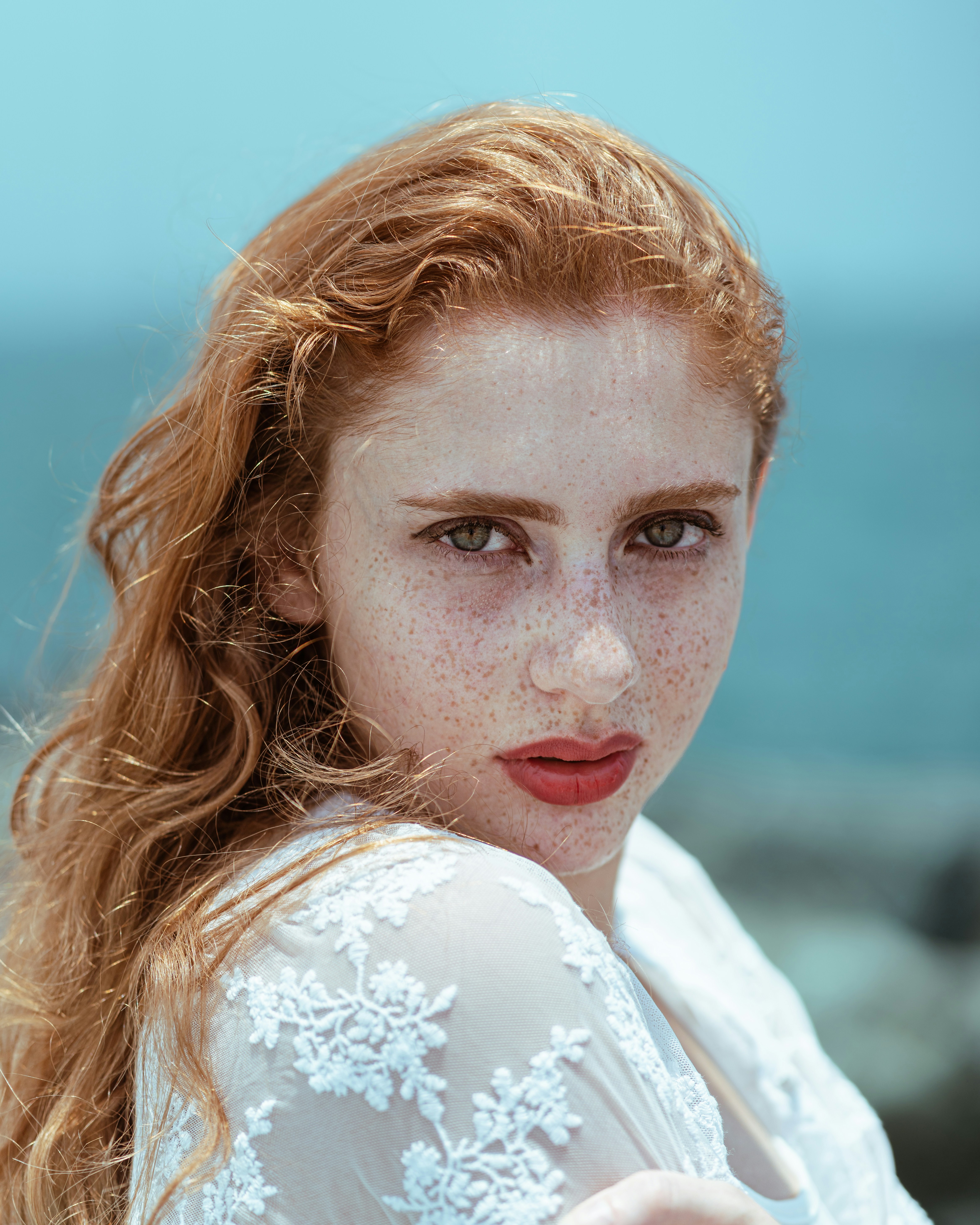 Mulher ruiva olha atentamente para a câmera.
