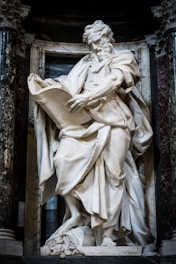 Marble statue of a man reading a scroll.