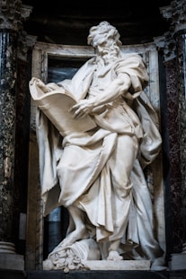 Marble statue of a man reading a scroll.