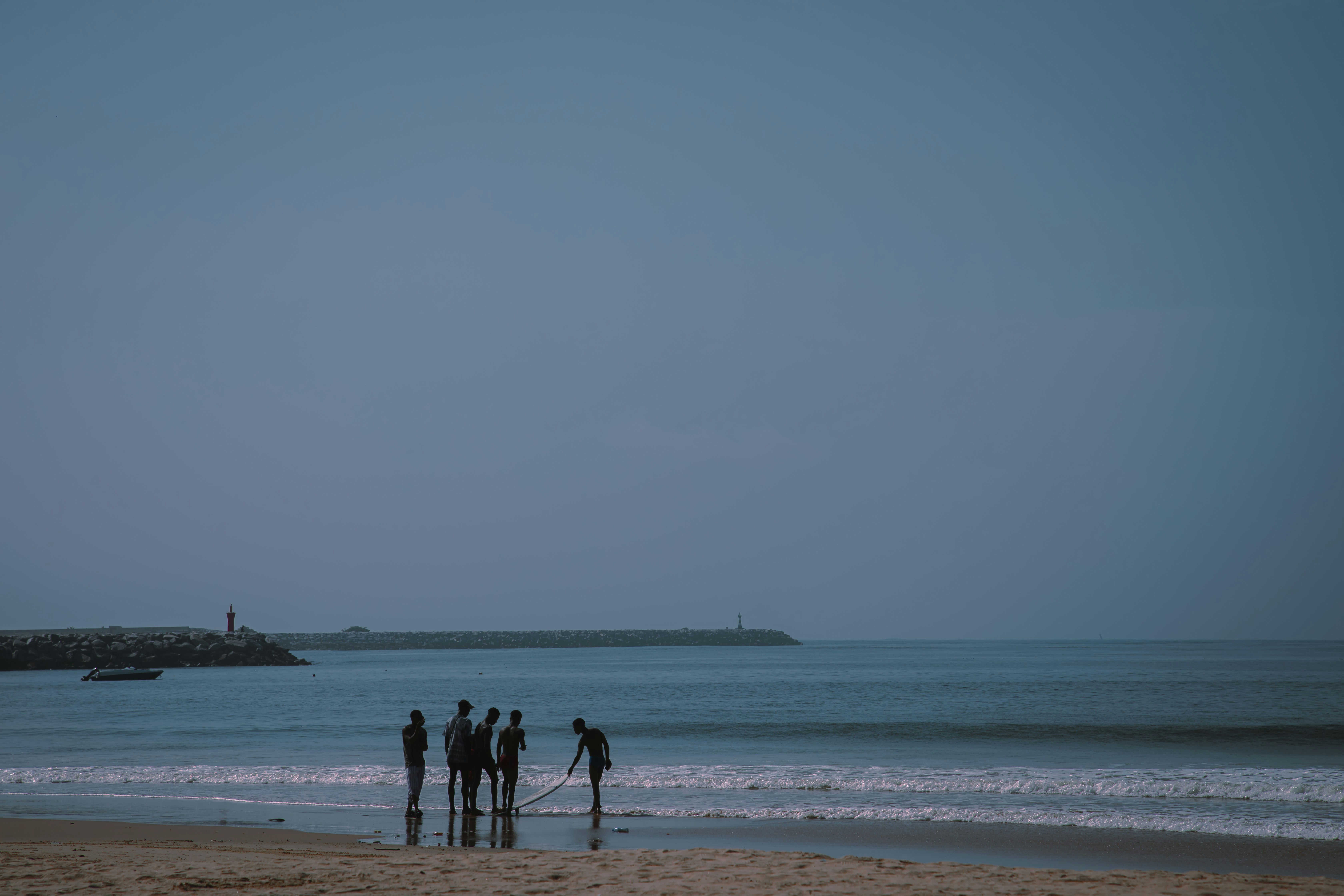 People stand at the beach, gazing at the water.