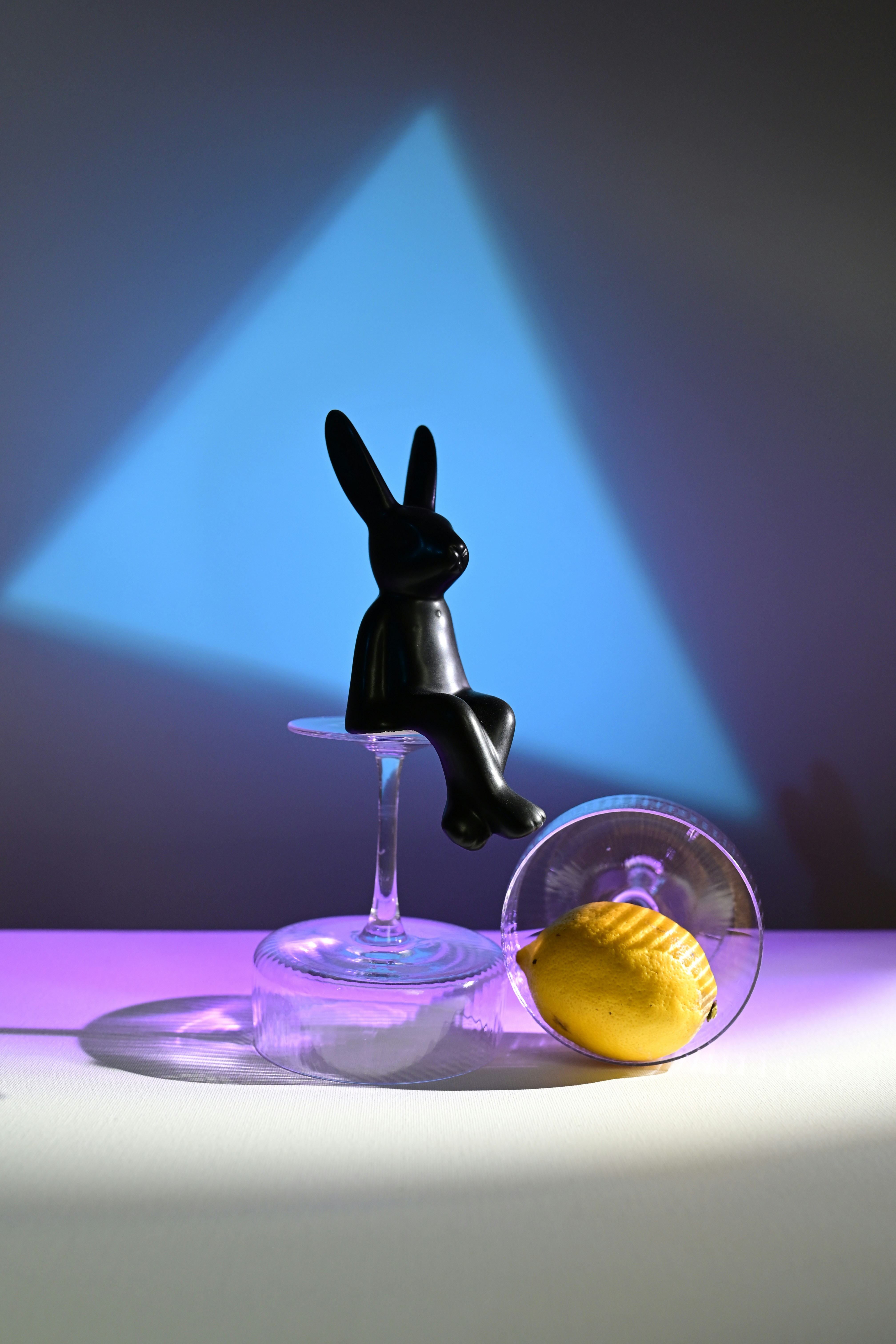 A black rabbit statue sits next to a lemon.