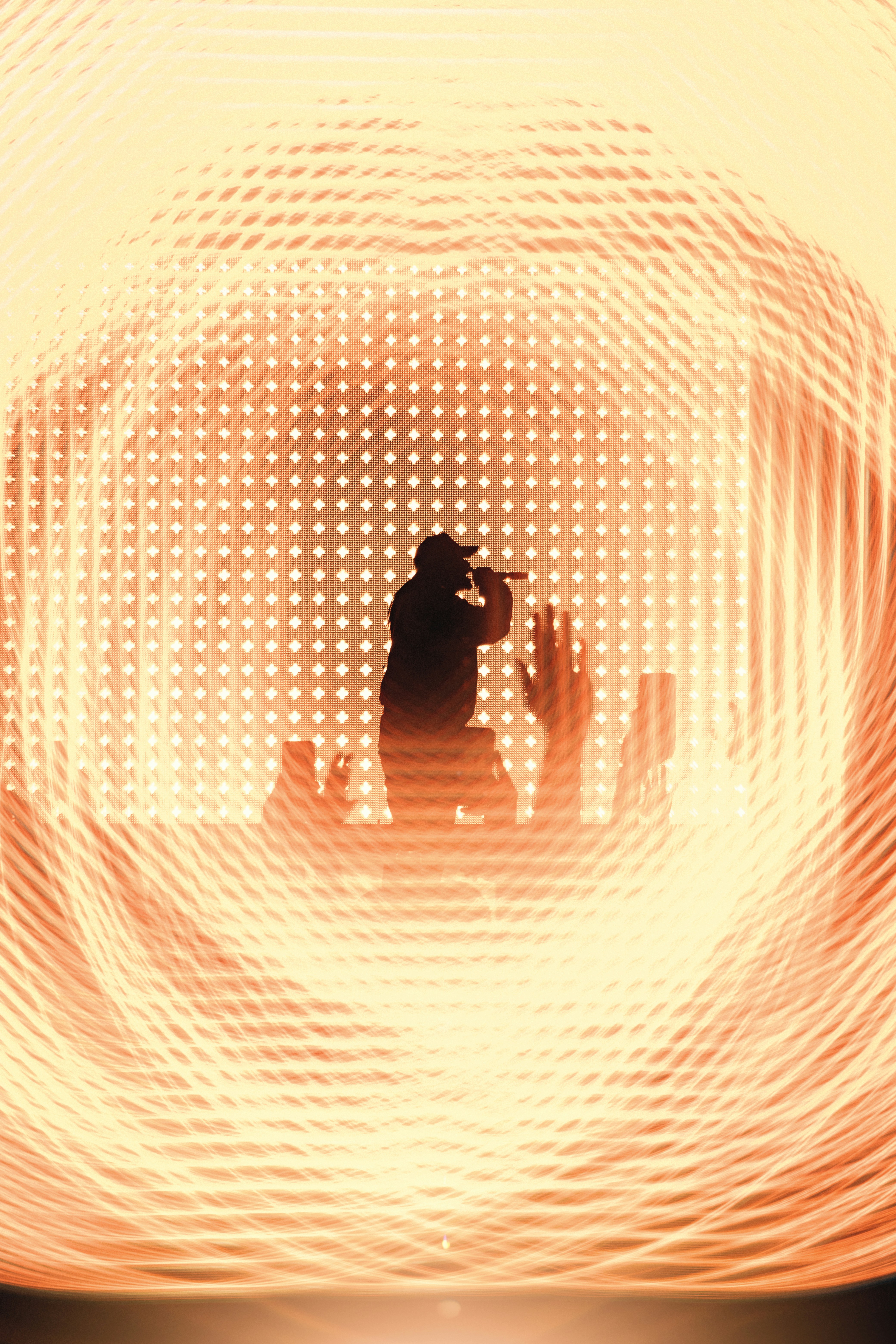 A silhouette sings on stage amidst light.