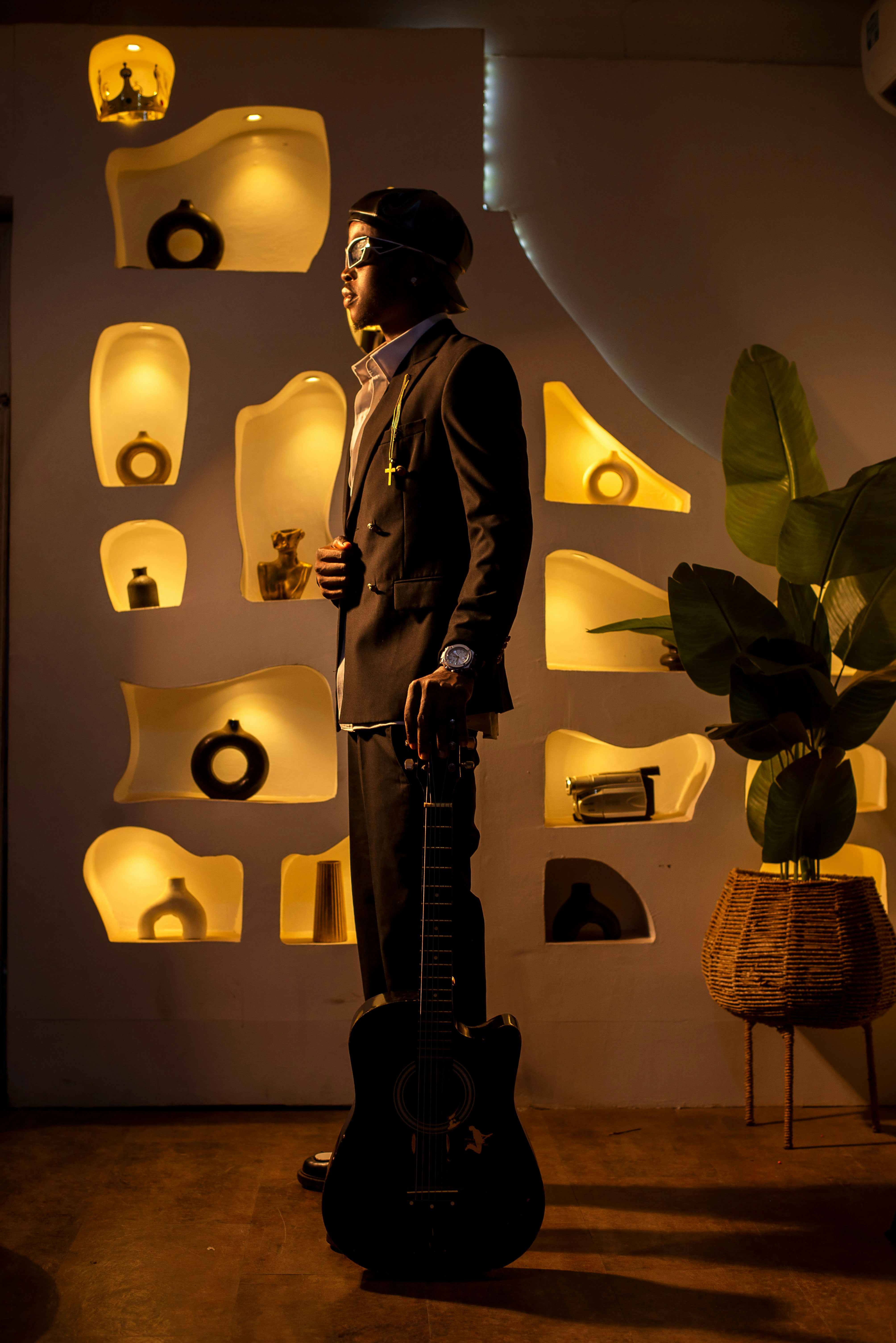 A stylish man poses with a guitar.