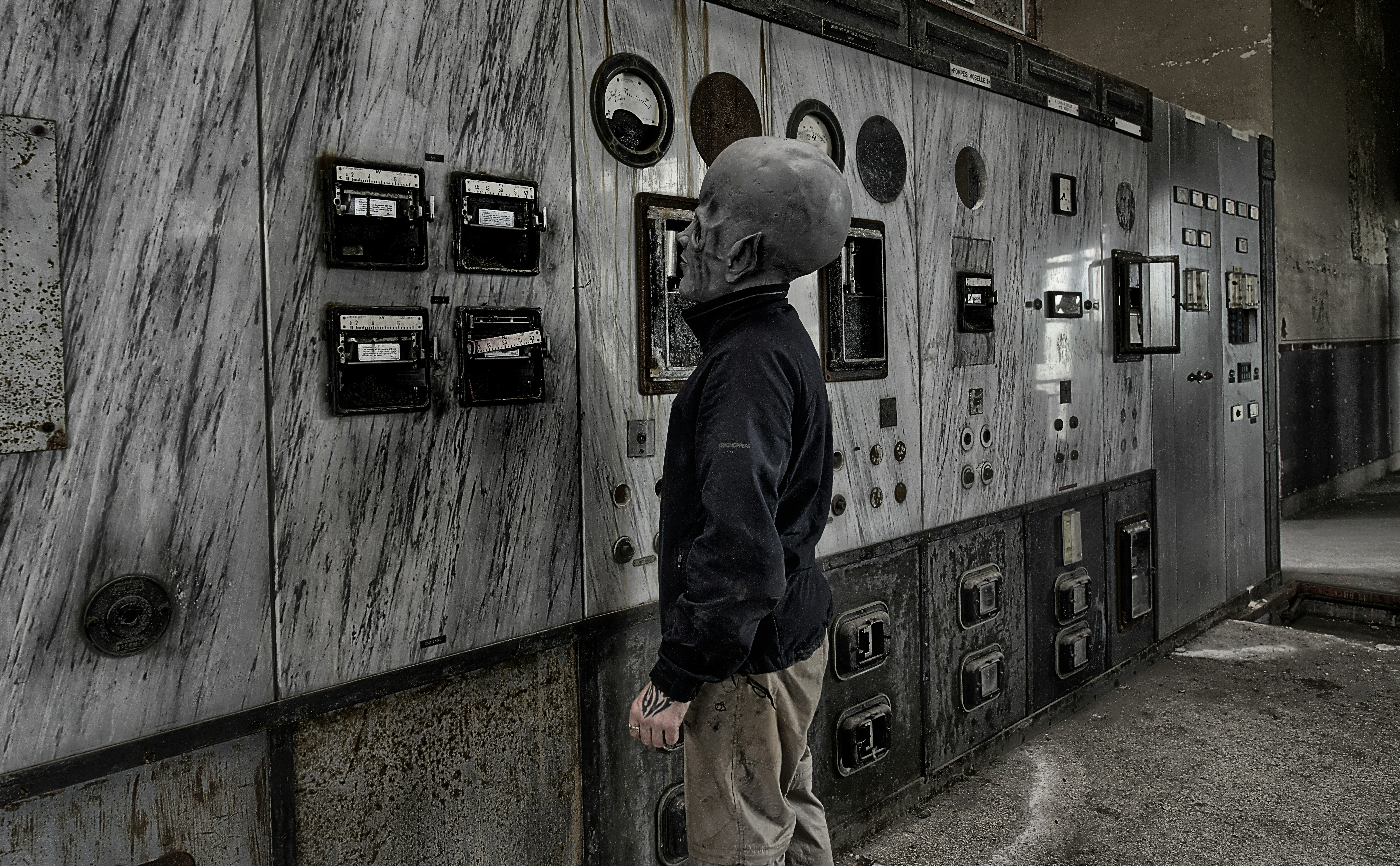 A person in a mask stands before control panels.