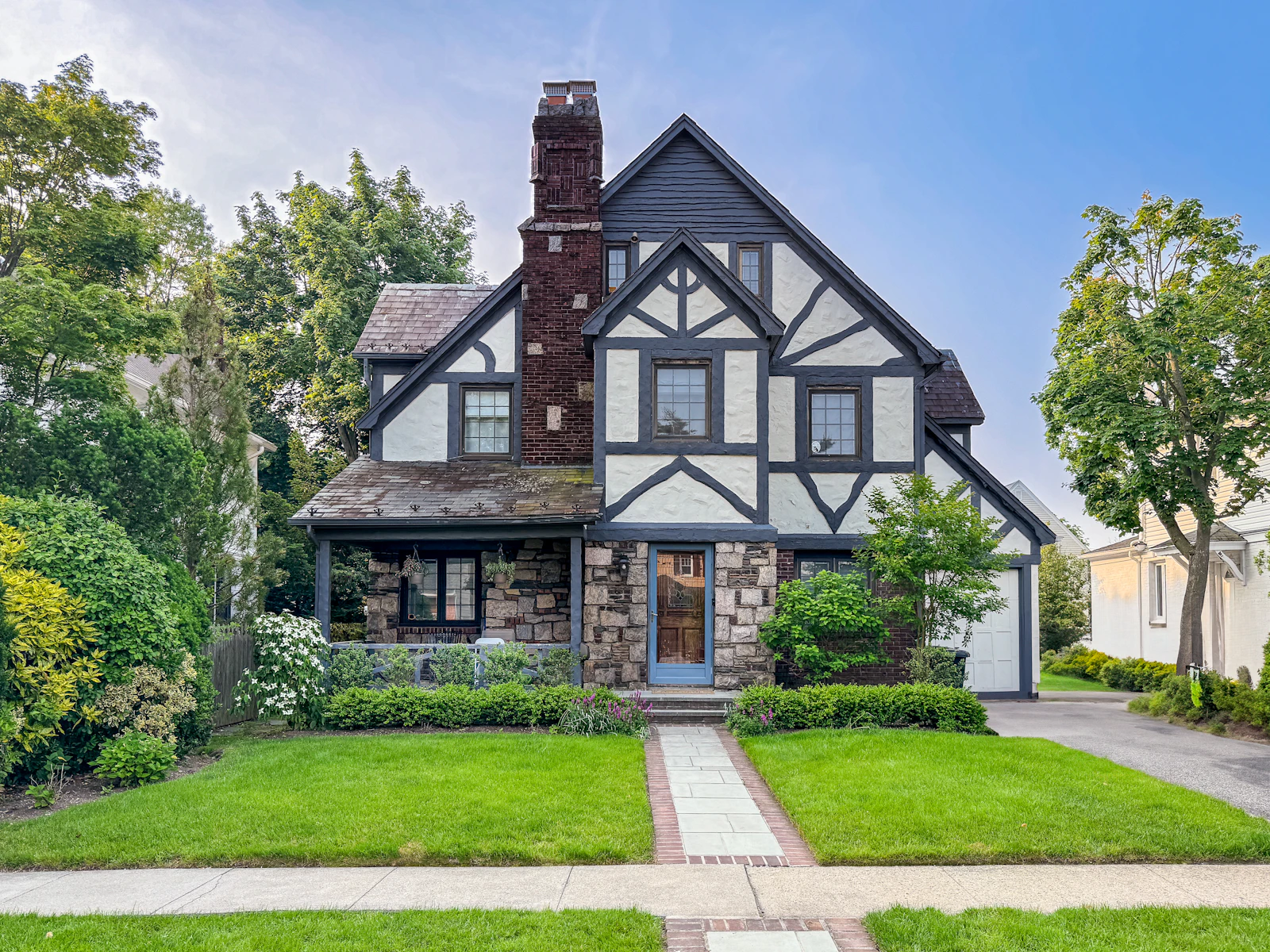 Tudor style home with a steep shingled roof and stone detailing in Lakewood Dallas