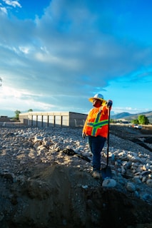Construction worker posing with a shovel under a blue sky.