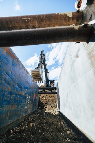 An excavator scoops dirt between large containers.