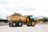 A yellow dump truck is hauling dirt.