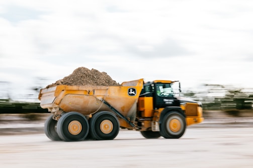 A yellow dump truck is hauling dirt.