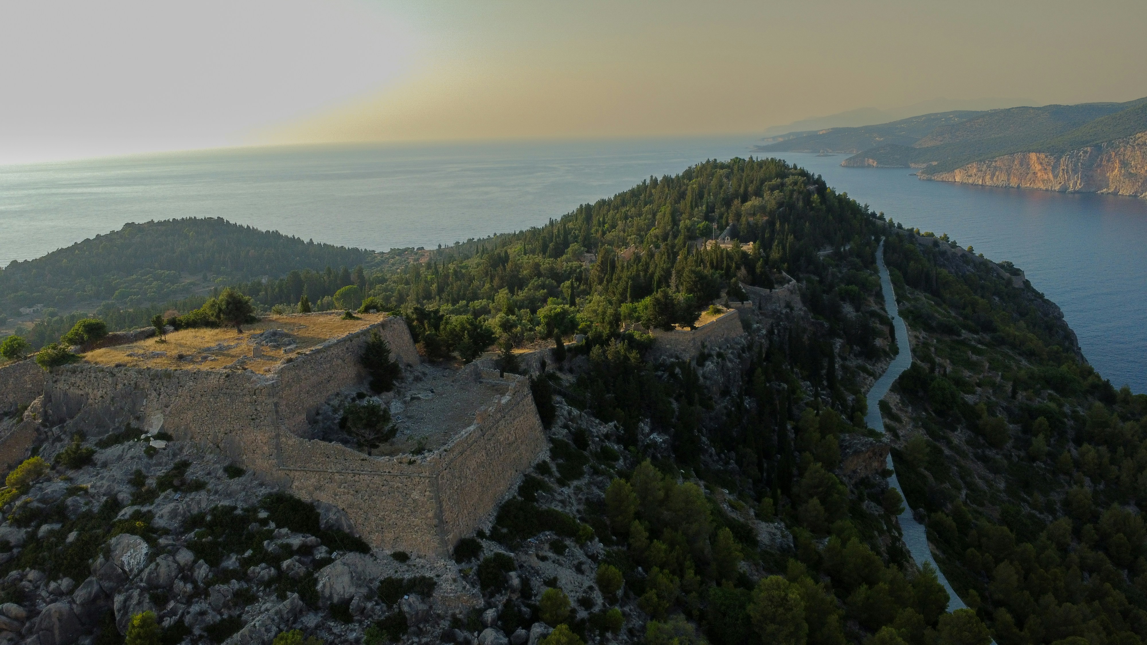 Ancient castle ruins overlook the sea and mountains.