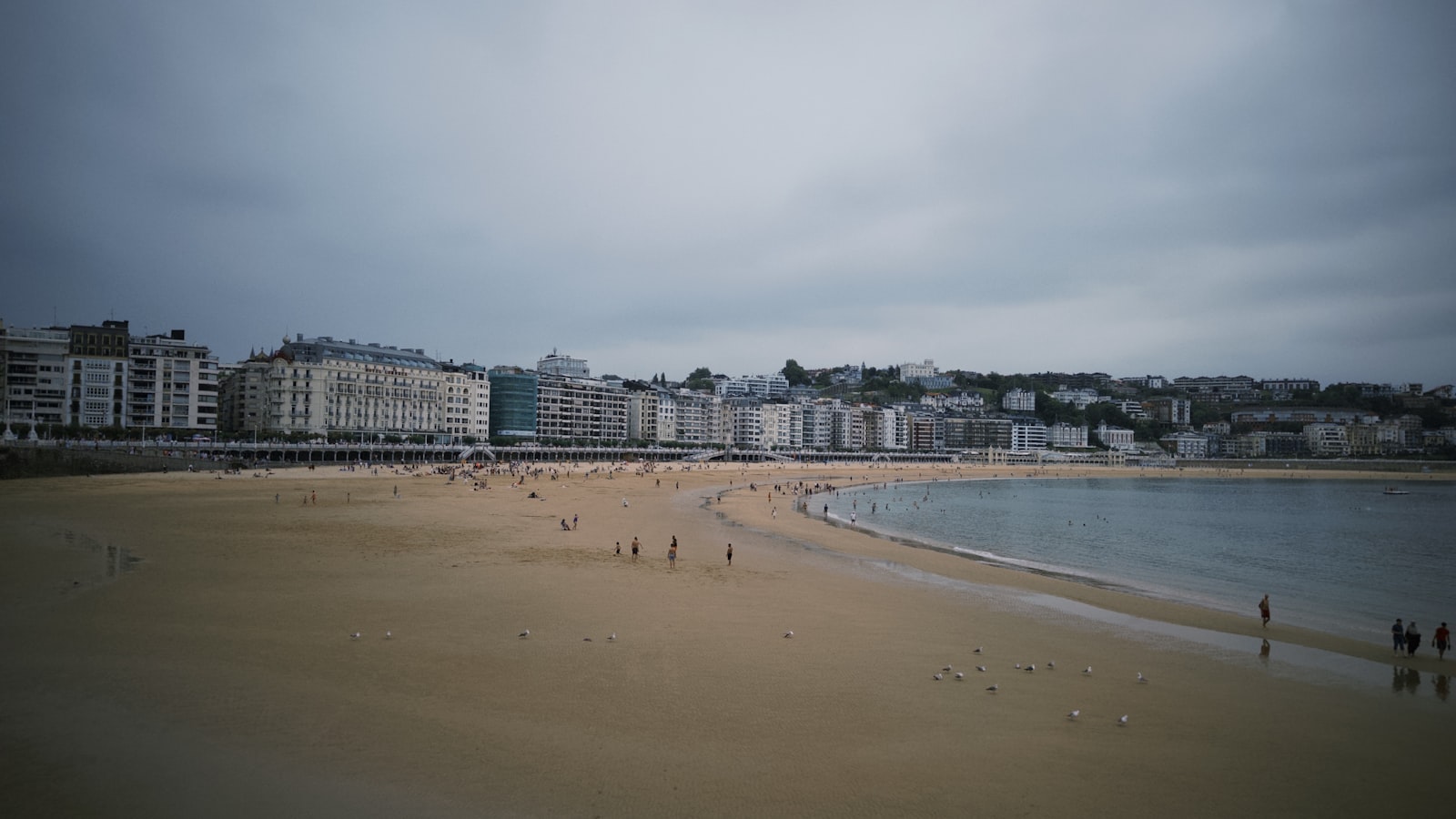 Playa de La Concha en San Sebastián con cielo nublado y edificios del paseo al fondo