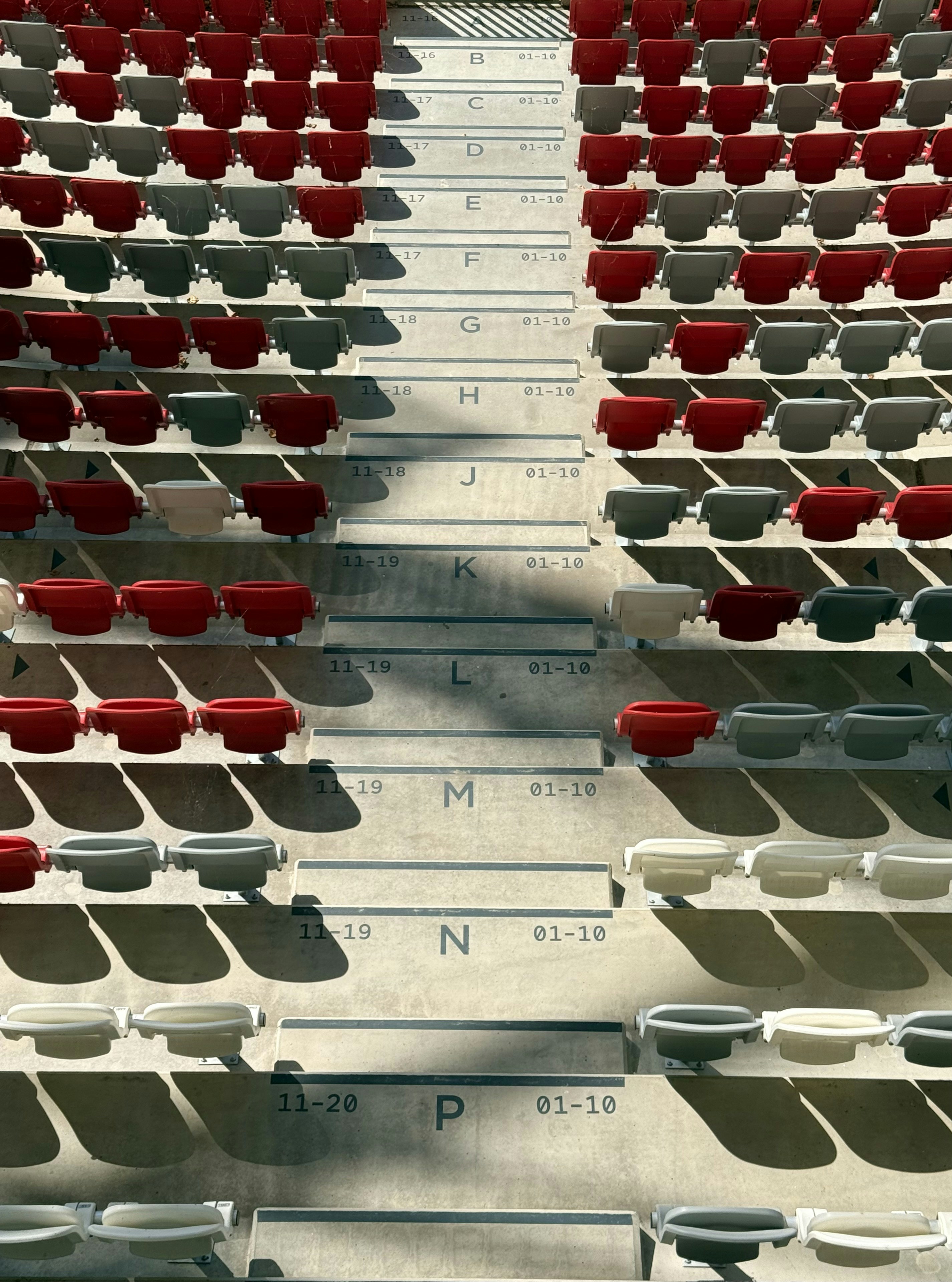 Fileiras de assentos de estádio, sombras e seções.
