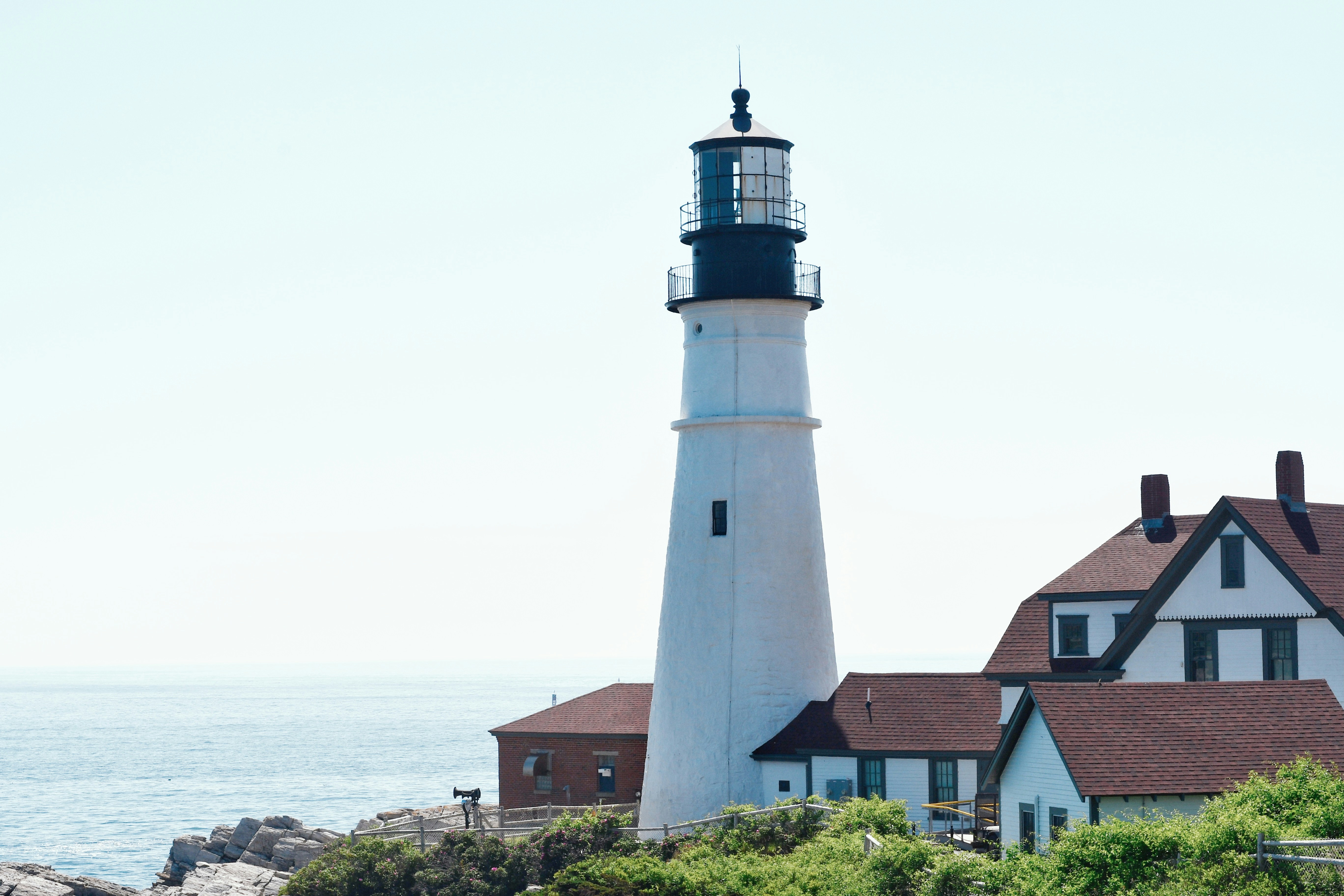 A lighthouse stands tall beside buildings.