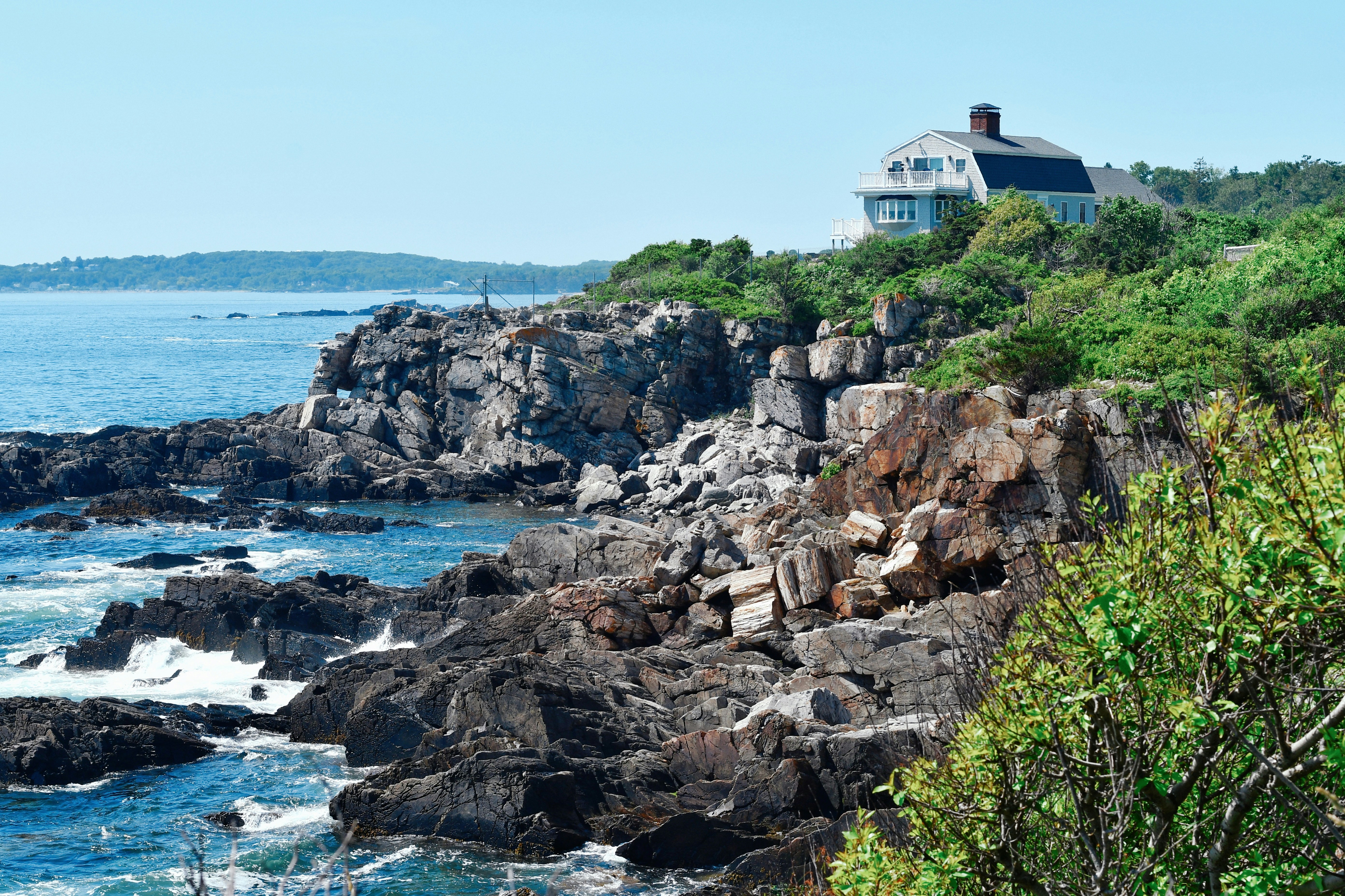 A house sits atop a rocky cliff overlooking the ocean.