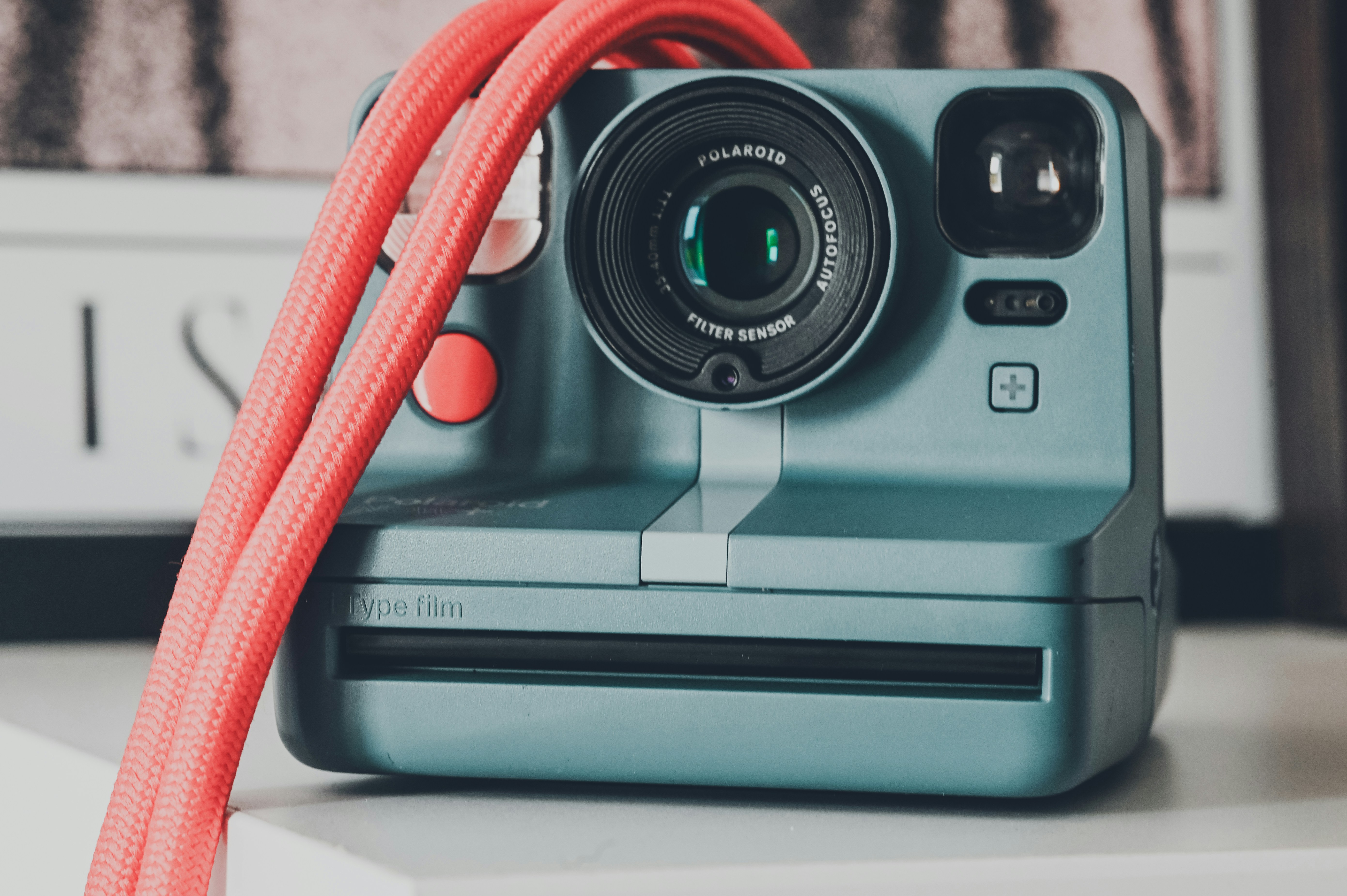 A blue polaroid camera with a red strap.