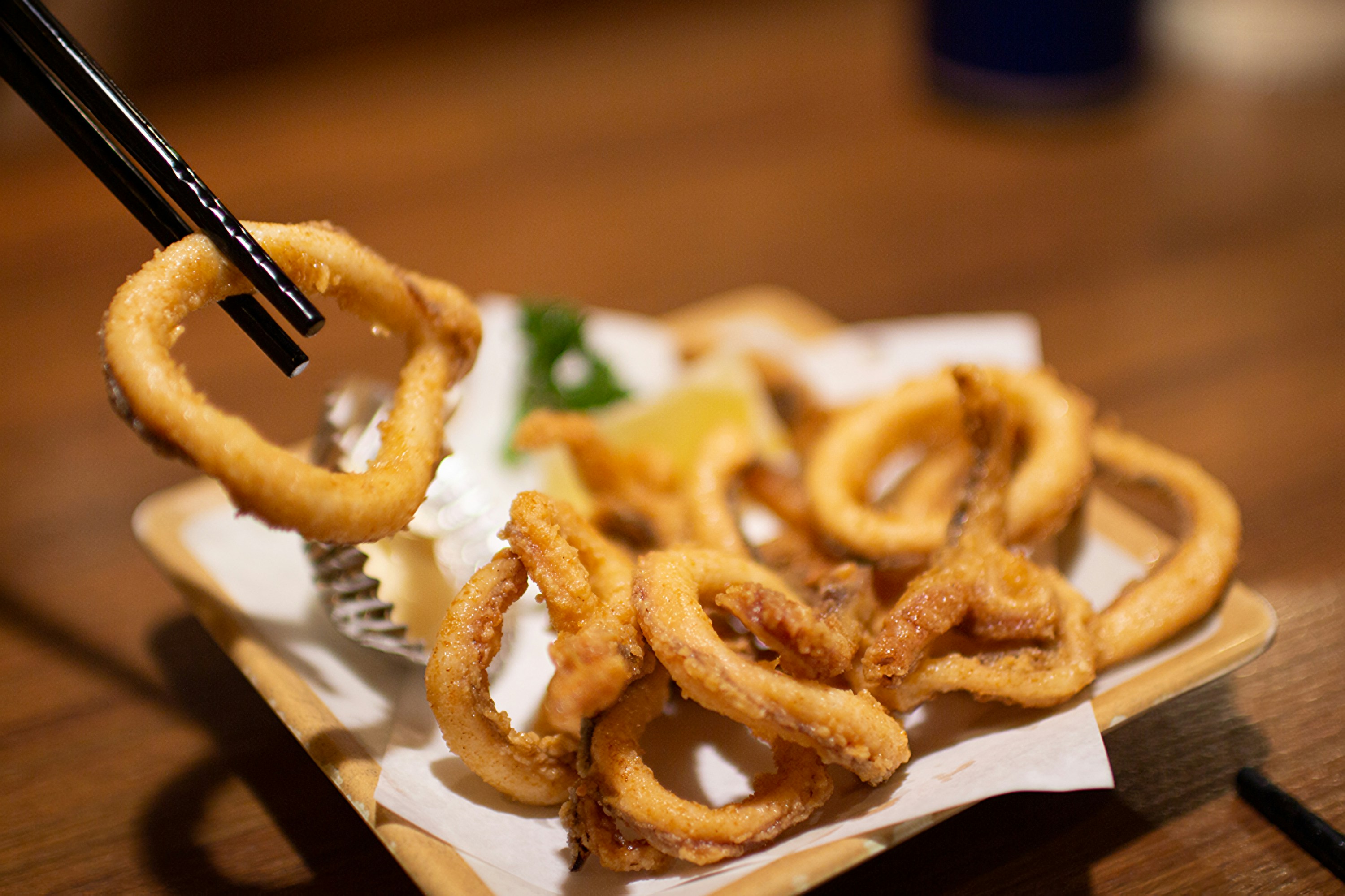 Fried calamari rings are being picked up with chopsticks.