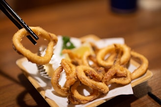 Fried calamari rings are being picked up with chopsticks.