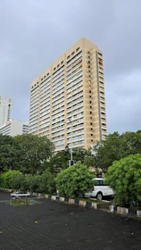 A tall building rises above lush greenery.