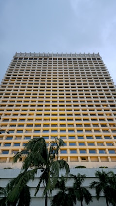 A tall building with many windows underneath a cloudy sky.