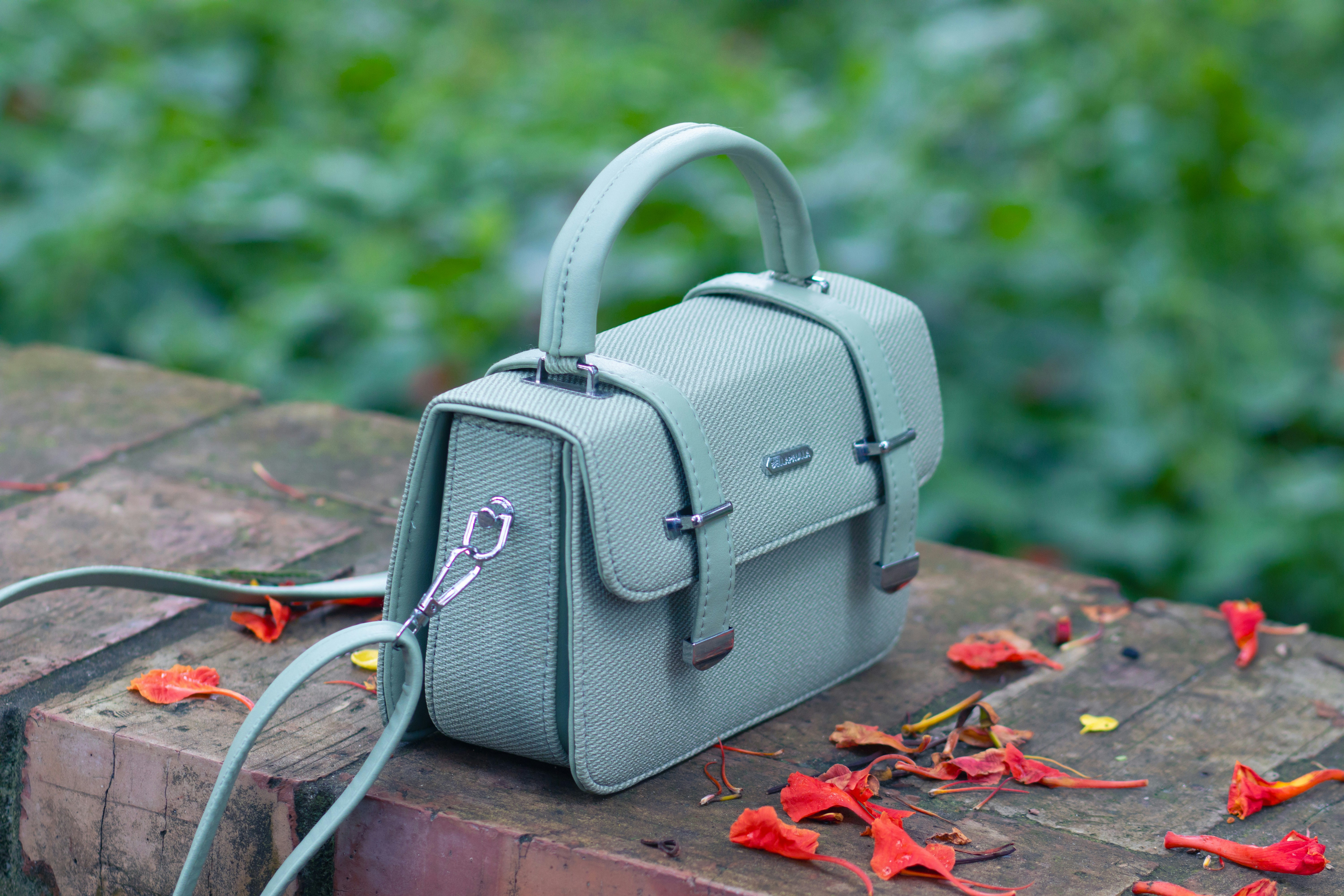 A stylish handbag sits outdoors on a stone wall.