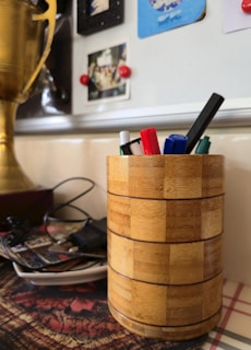 A wooden pencil holder filled with pens.