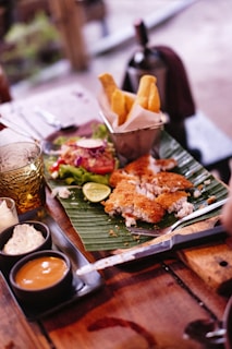 Delicious fish and chips with sauces on a wooden table.
