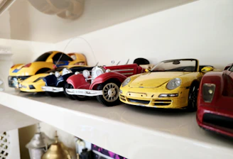 Toy cars are lined up on a white shelf.