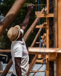 A carpenter measures wood on a construction site.