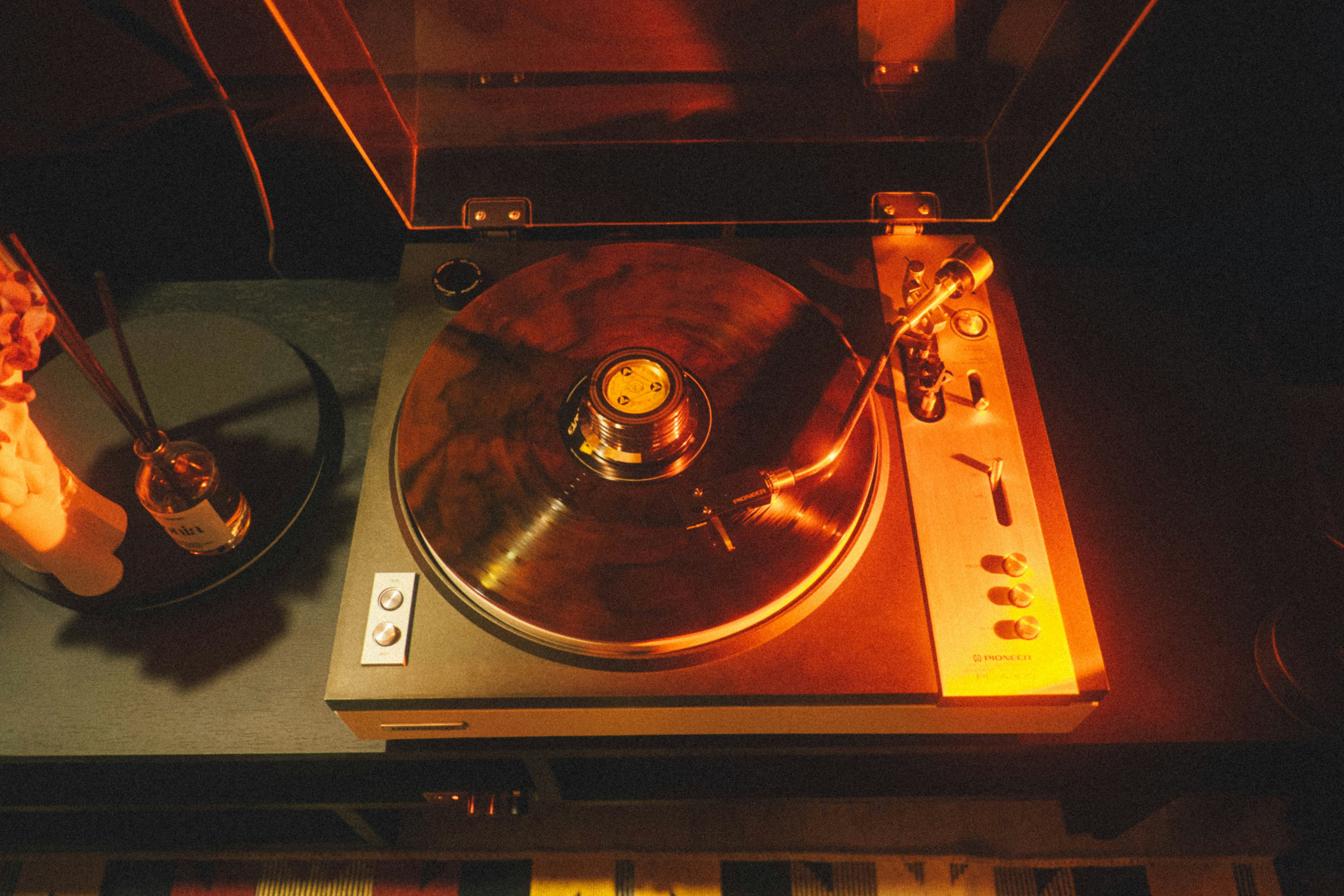 A record player plays vinyl, illuminated by light.
