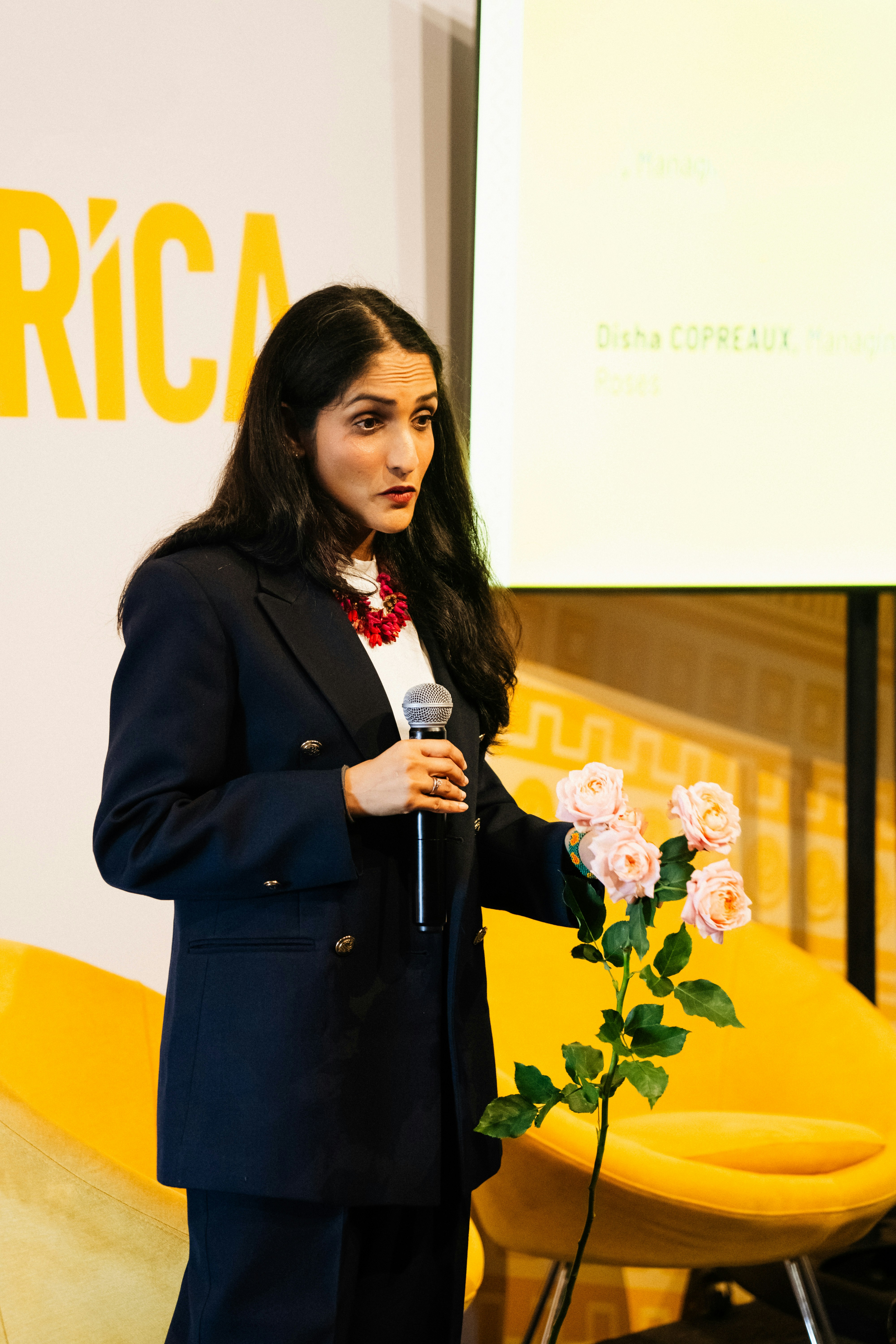 Woman speaks at a conference holding a microphone