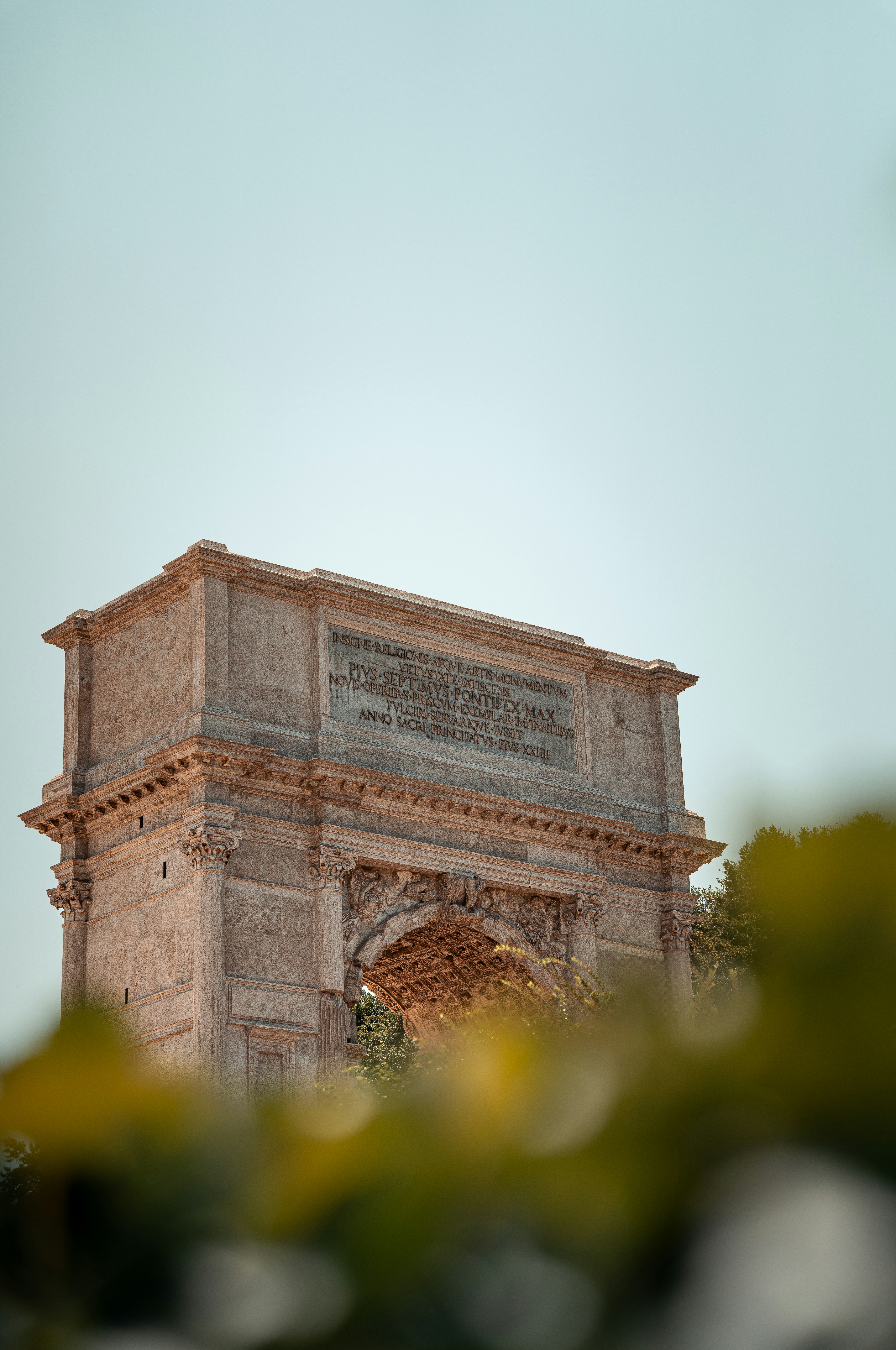 Arch of titus stands proudly against a clear sky.