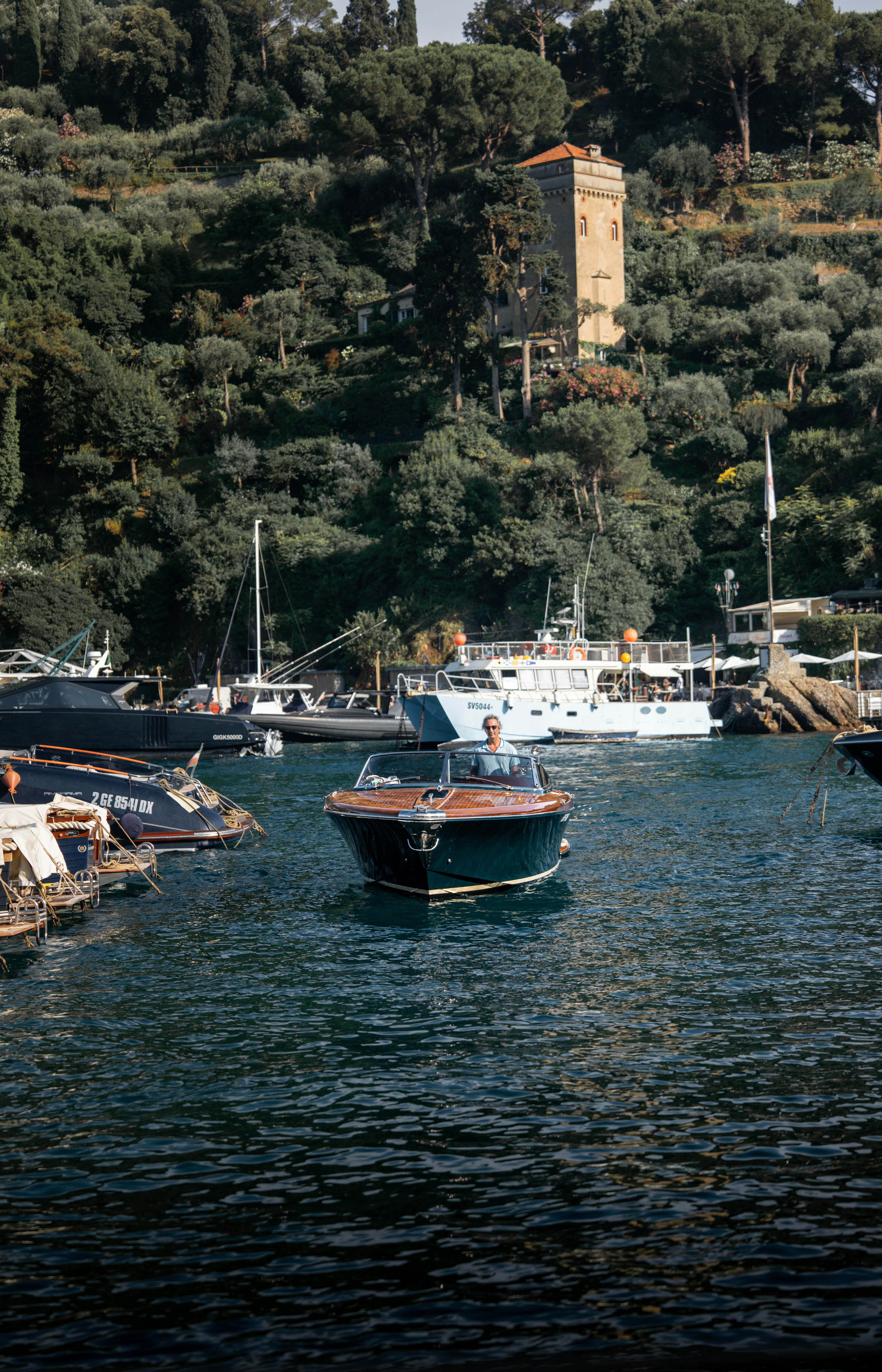 A wooden boat cruises in a scenic, coastal harbor.
