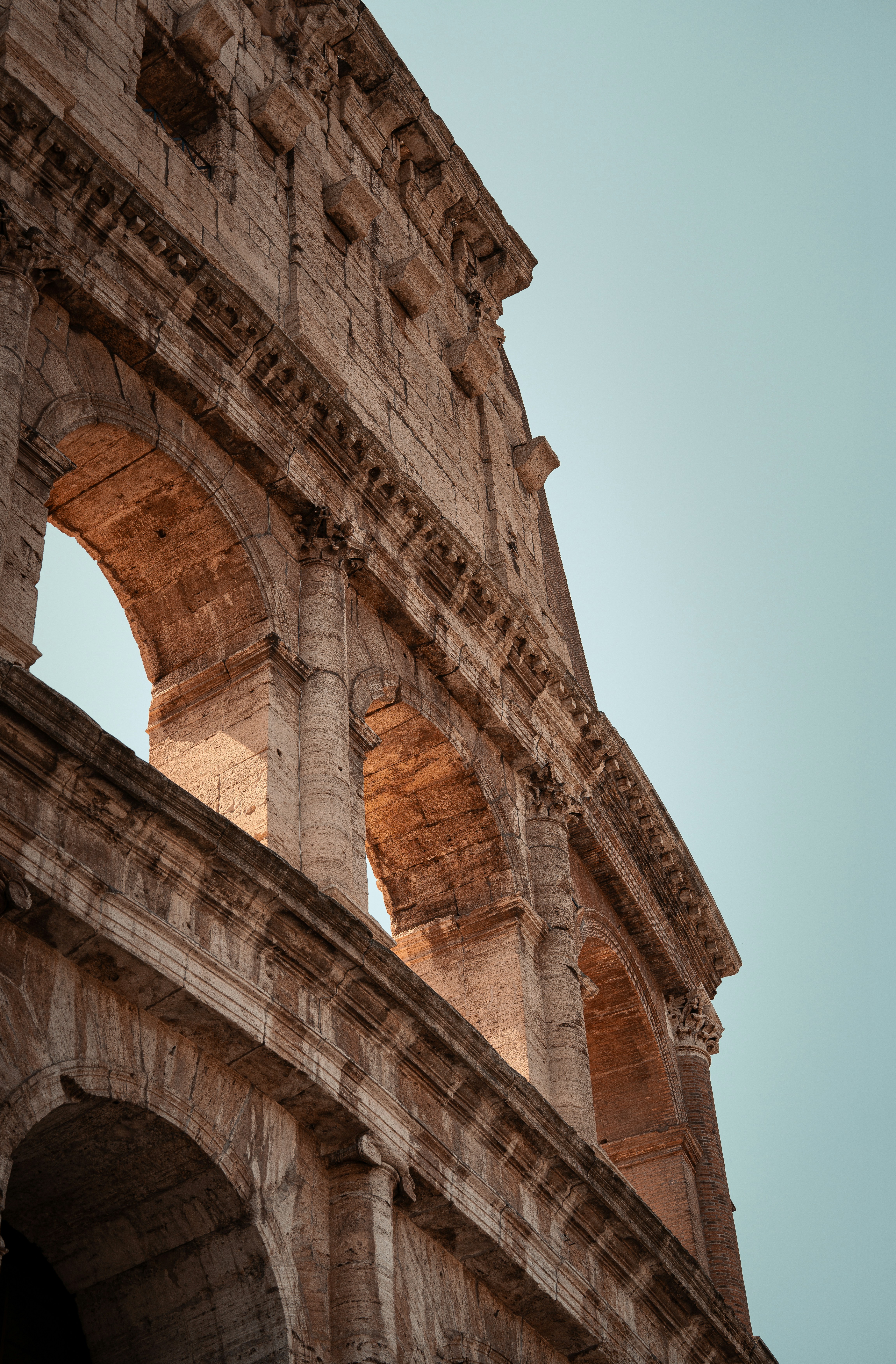The colosseum's arches stand tall under clear skies.
