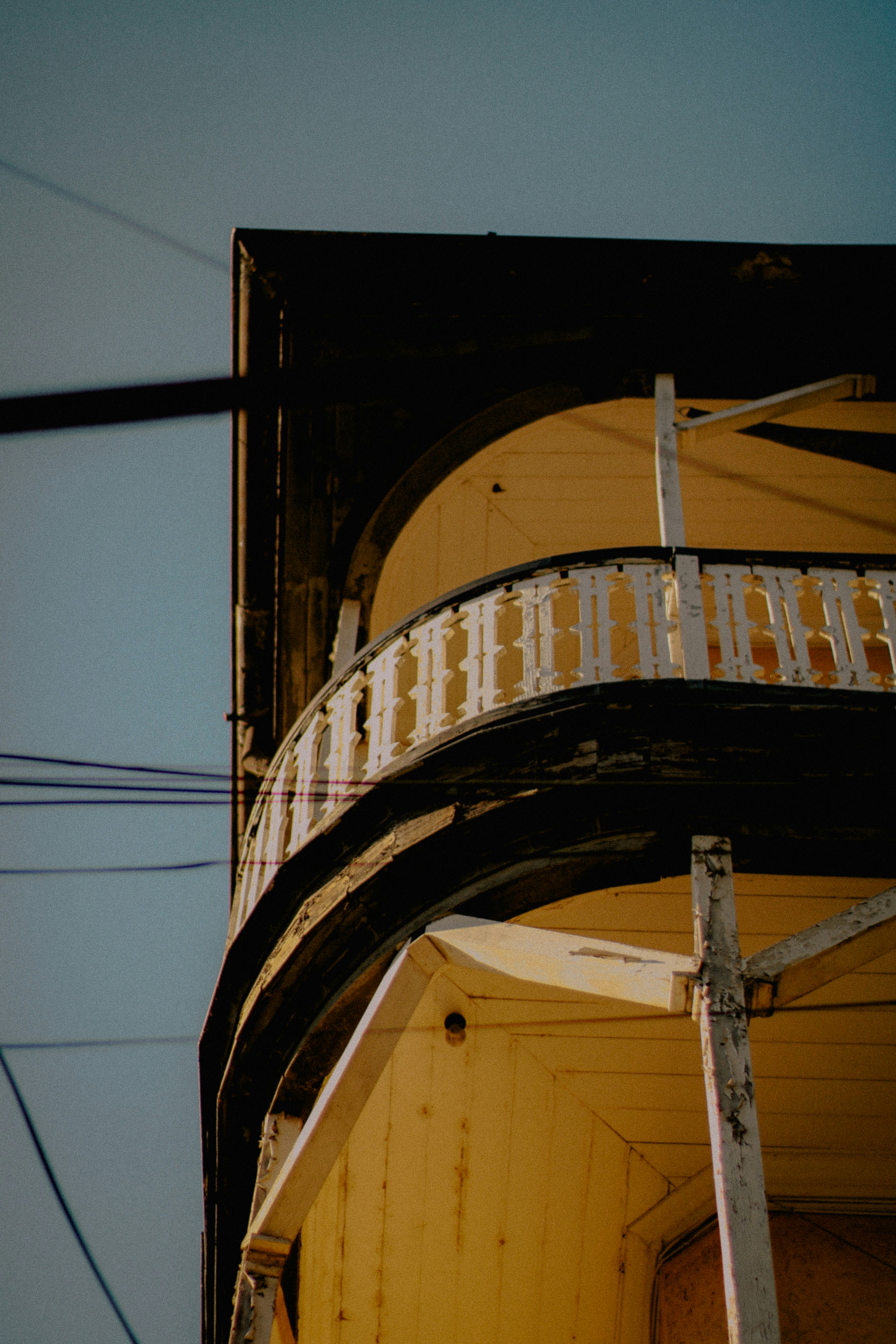 A corner balcony on an old, yellow building.
