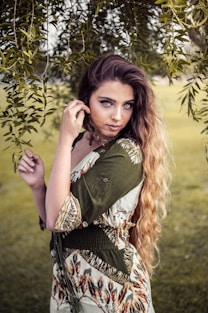 A woman poses elegantly outdoors with soft lighting.