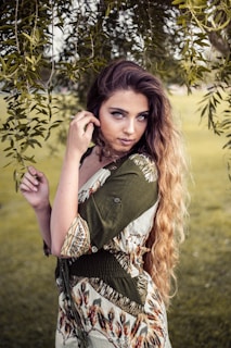 A woman poses elegantly outdoors with soft lighting.