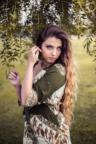 A woman poses elegantly outdoors with soft lighting.