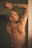A tattooed person poses with arms raised.