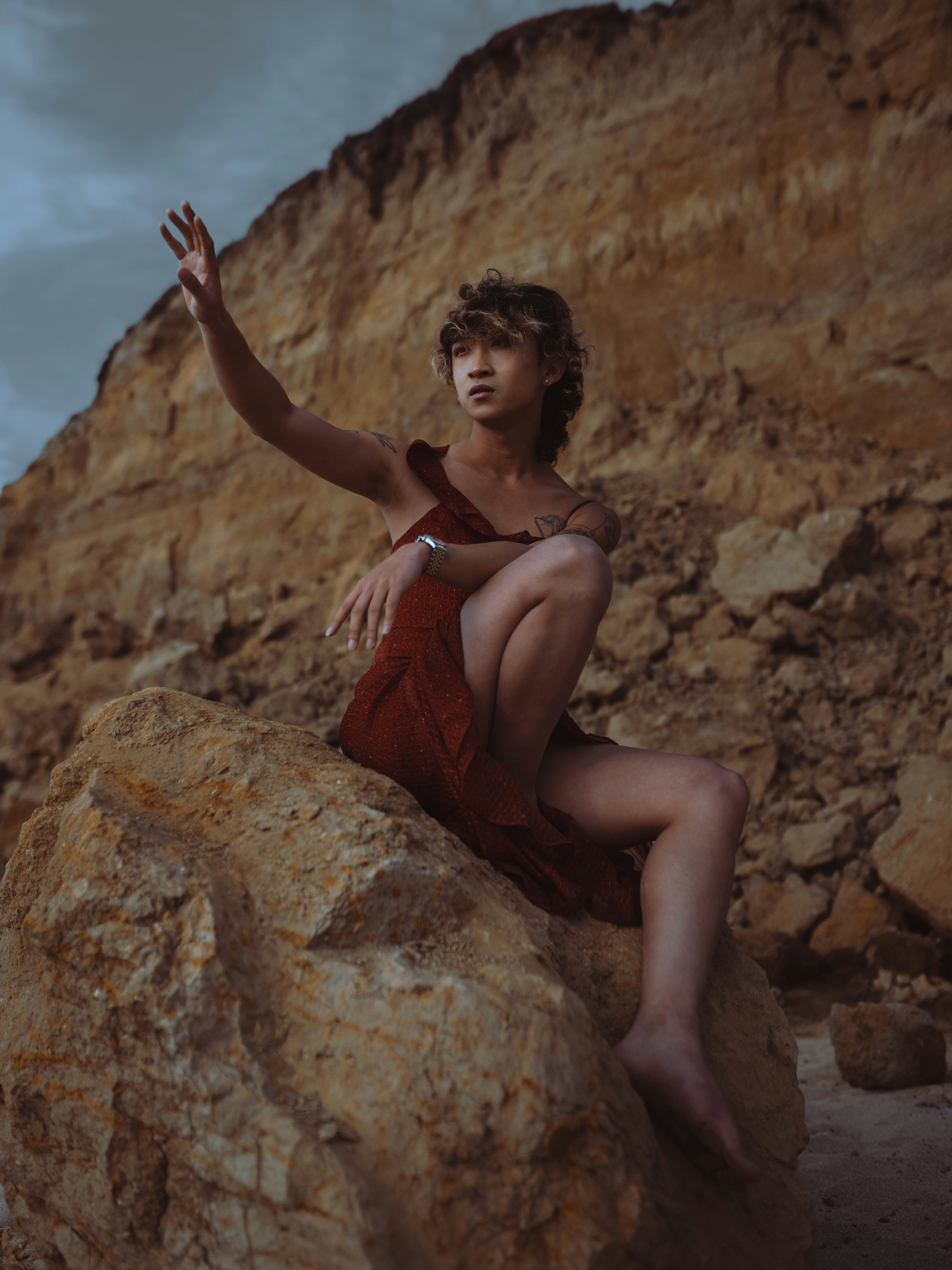 Woman in red dress poses on a rock.