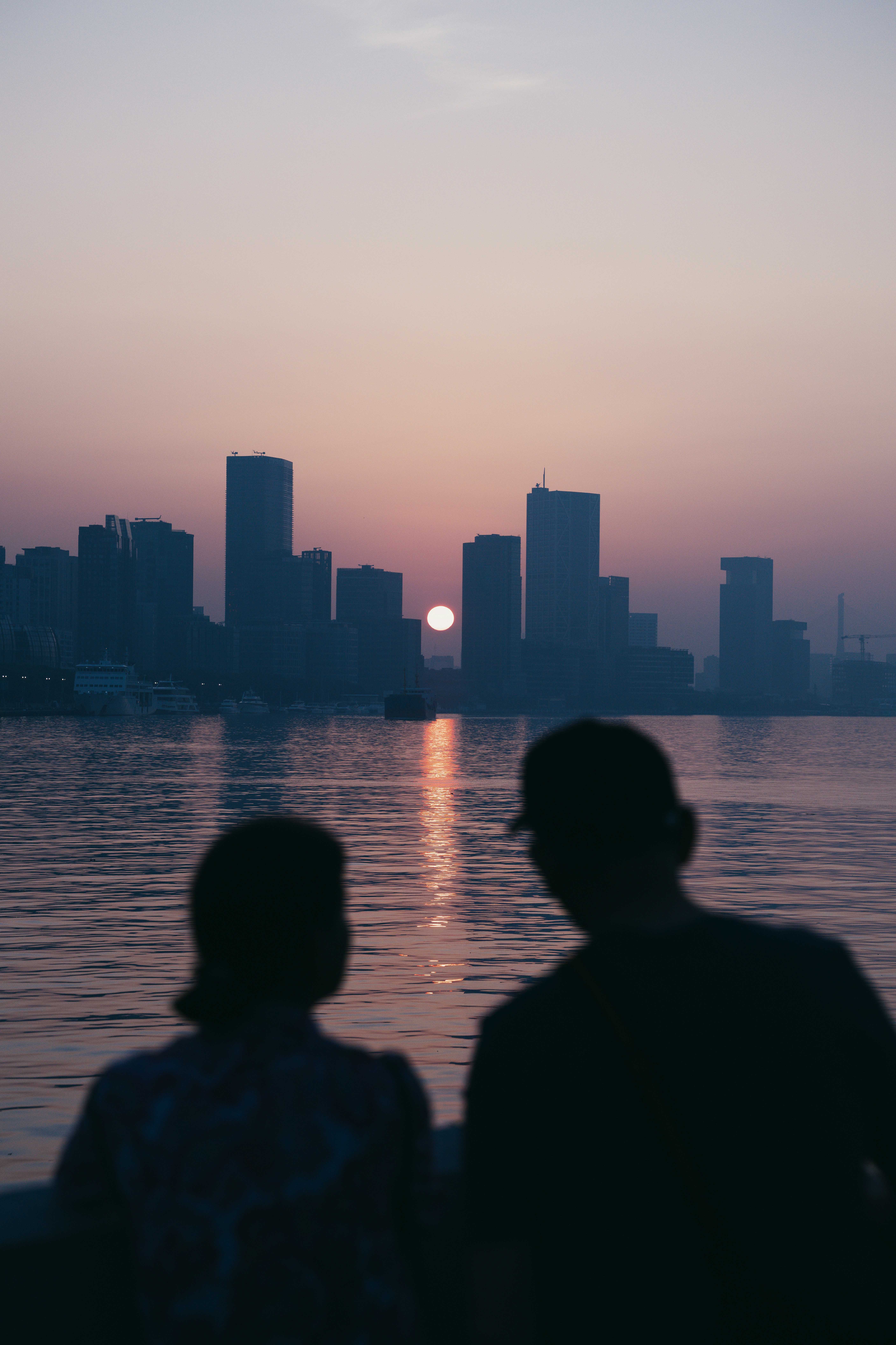 Couple watches the sunset over the city skyline.