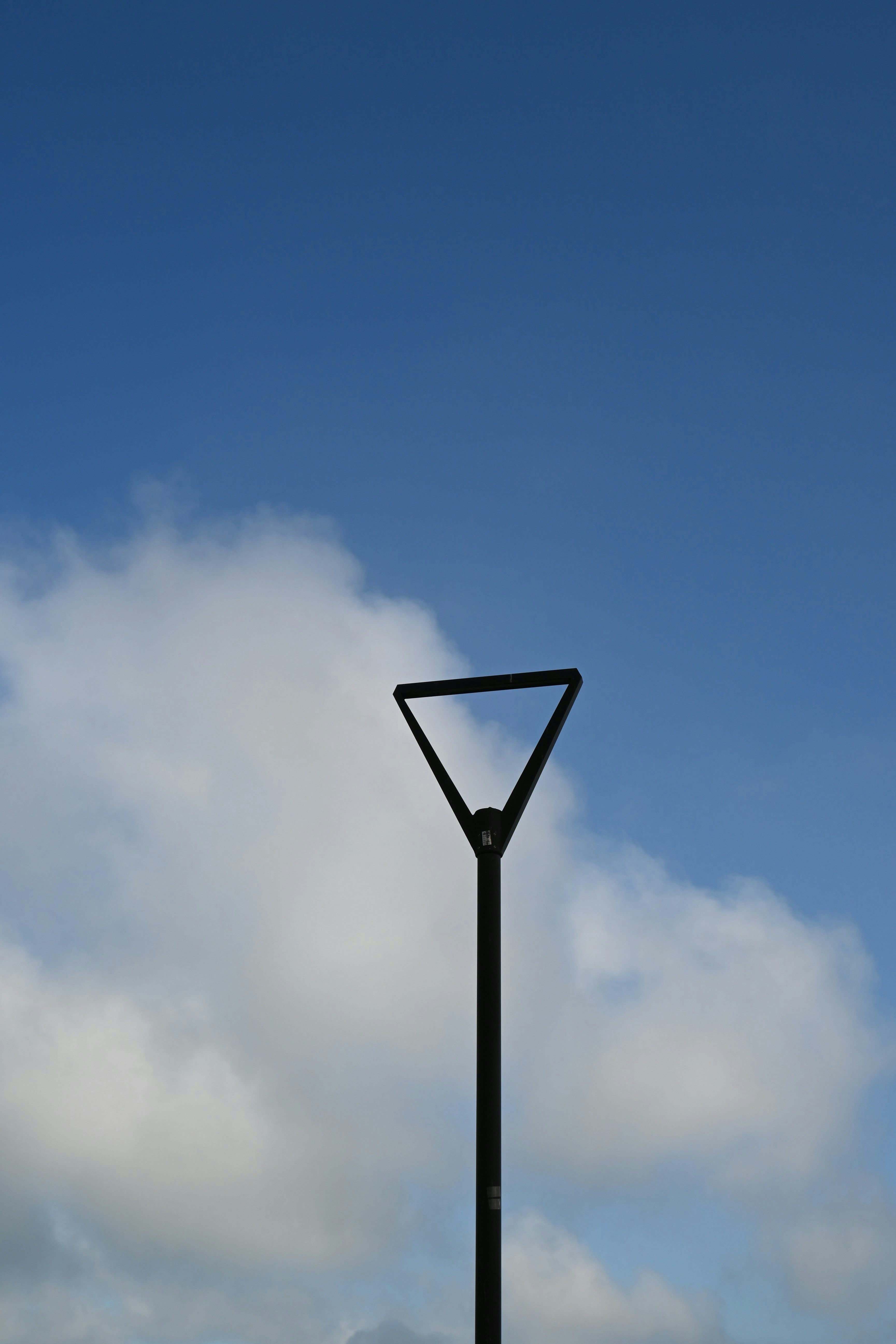 Street lamp against a blue sky with some clouds.