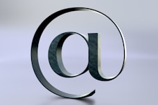 An at symbol is seen on a reflective surface.