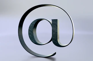 An at symbol is seen on a reflective surface.