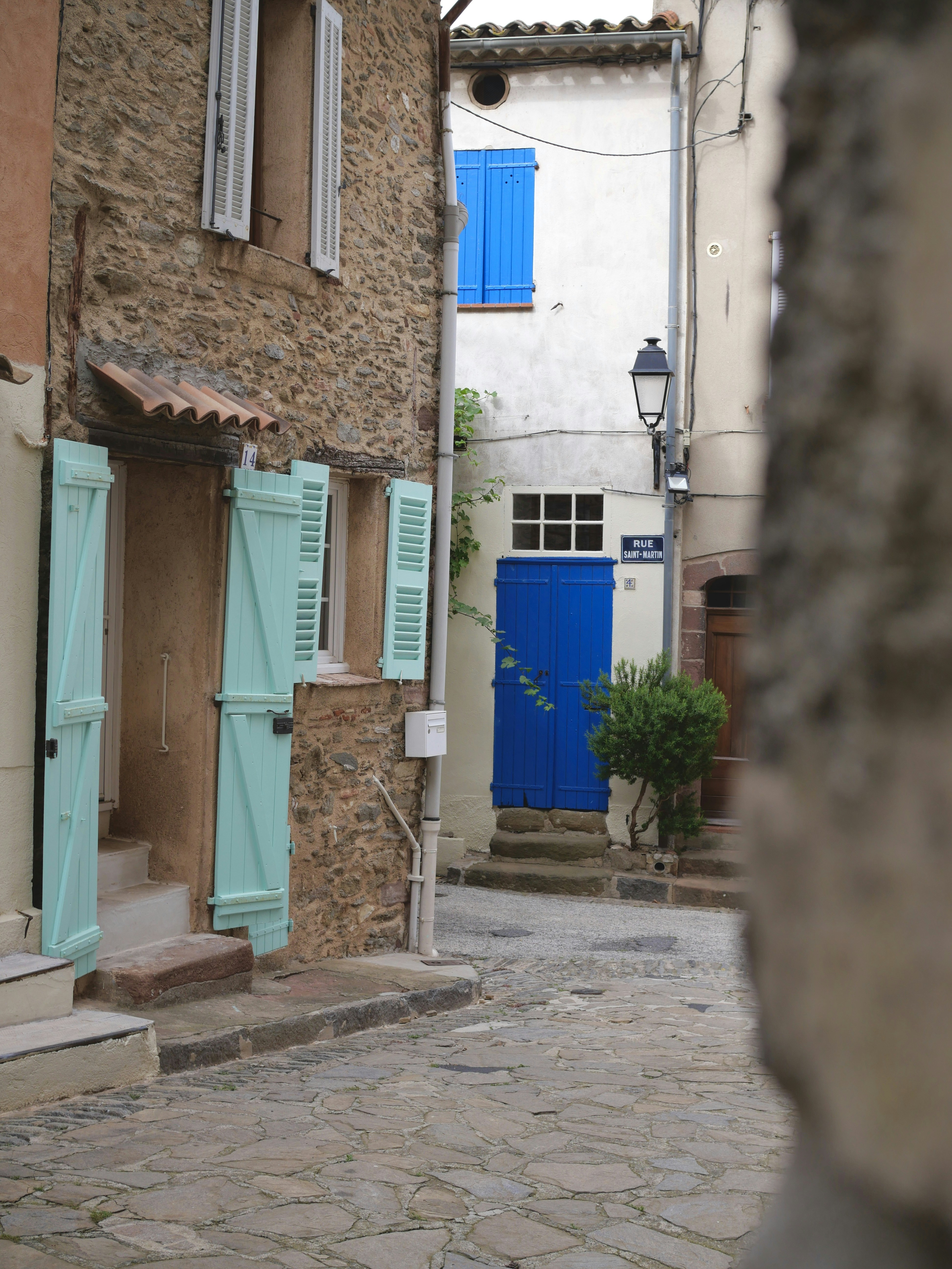 Cobblestone street with colorful shutters and doors.