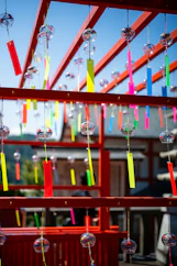 Colorful wind chimes hang from a red structure.