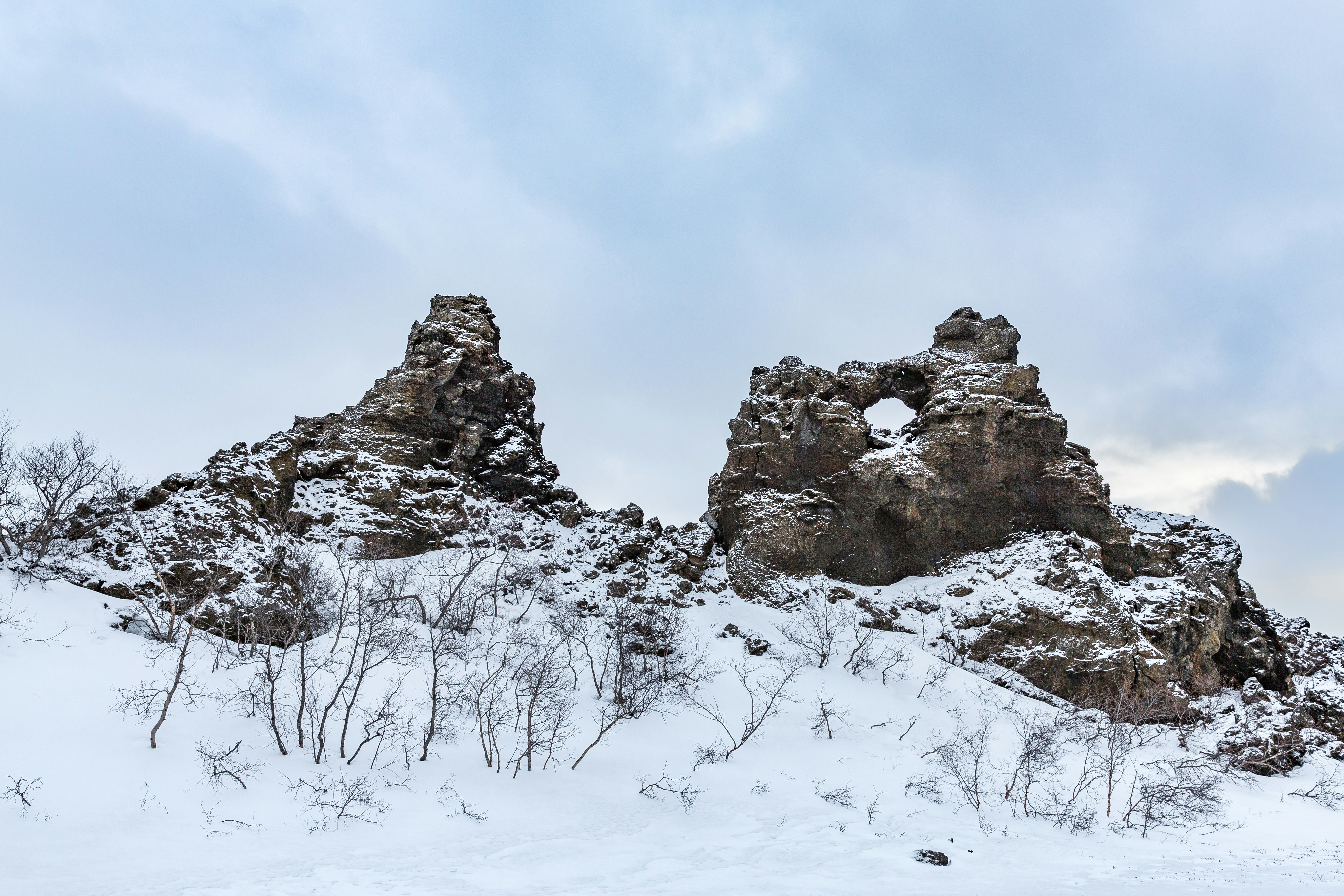 Snow-covered rocky formations under a cloudy sky.