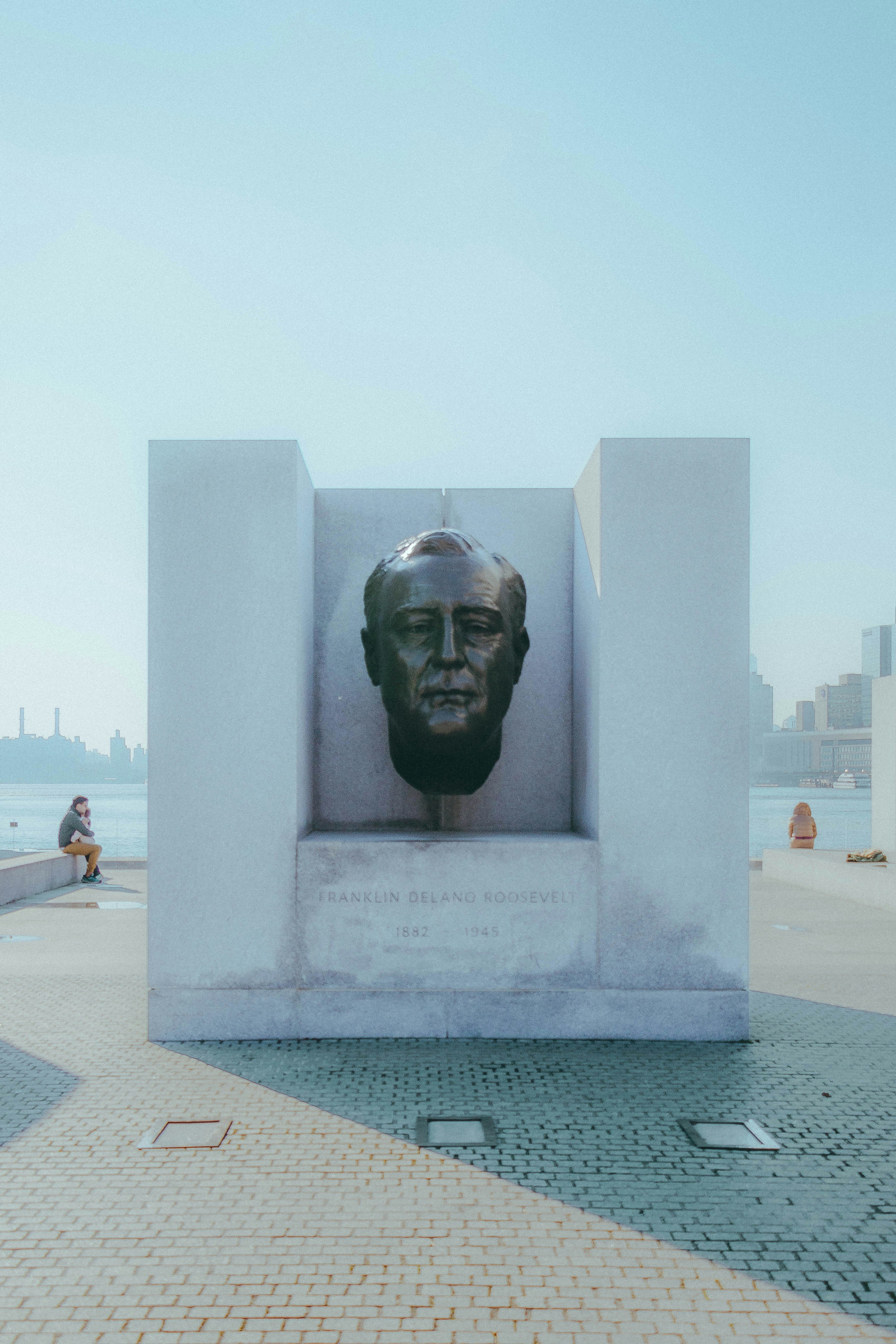 A bronze bust is framed in a square concrete structure.