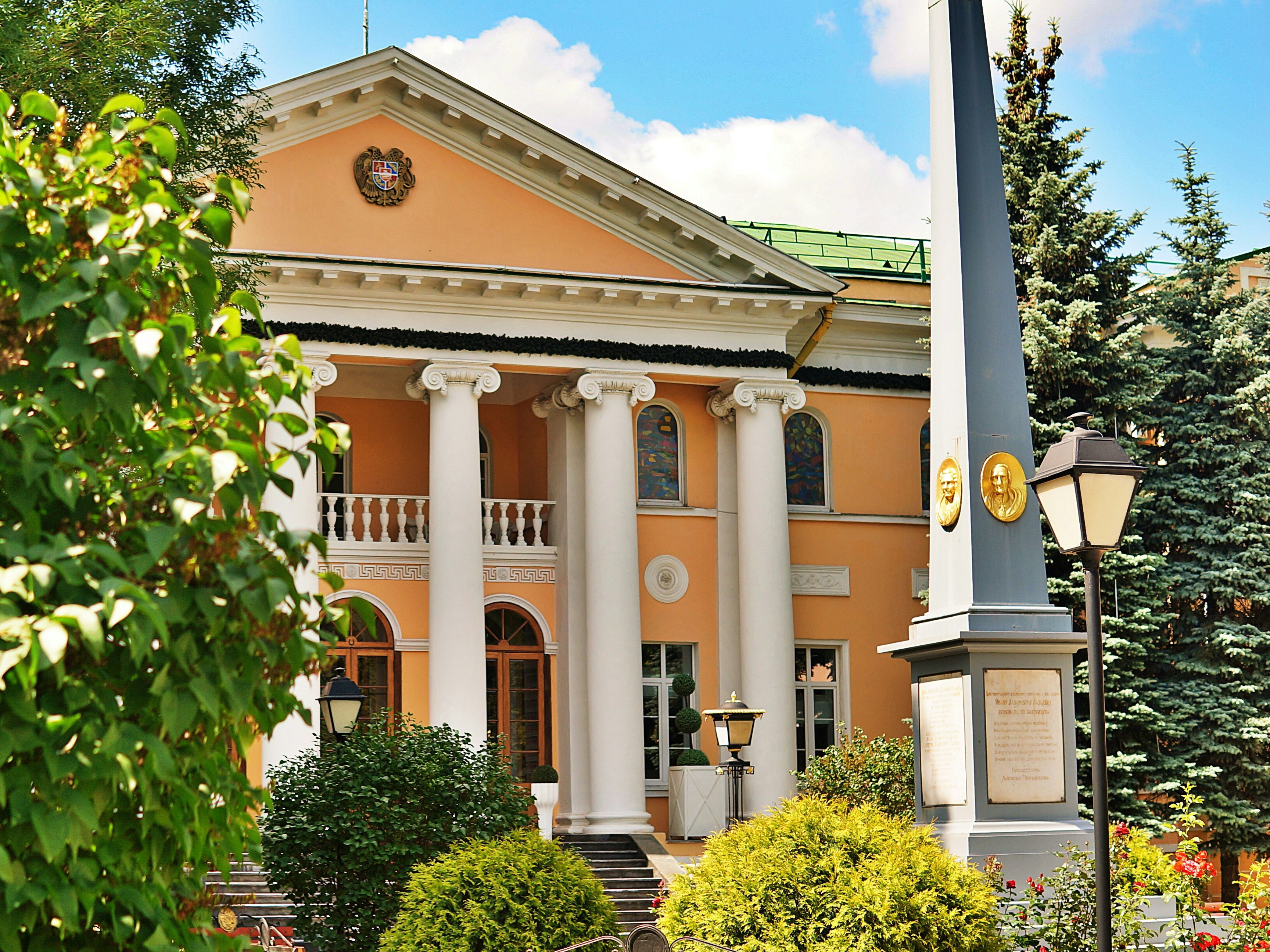 An elegant building stands with columns and a lamp.